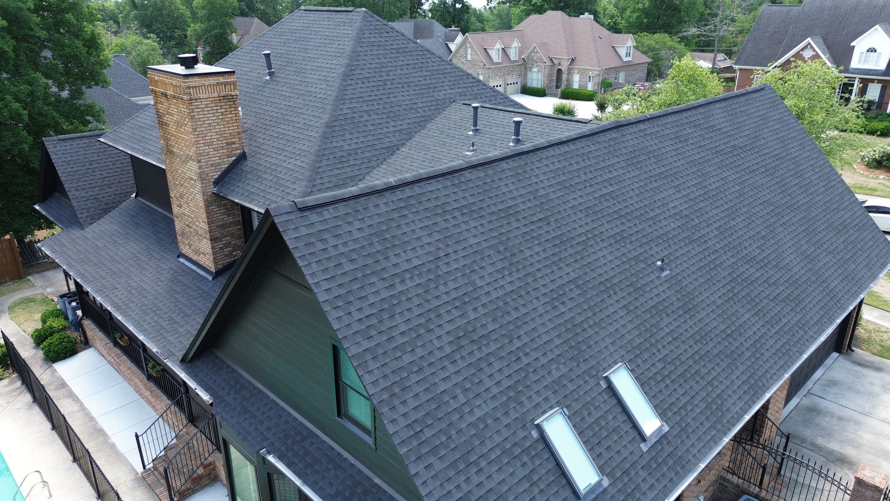 Aerial view of a completed roof replacement with new dark asphalt shingles on a home in Carisbrooke, Hoover.