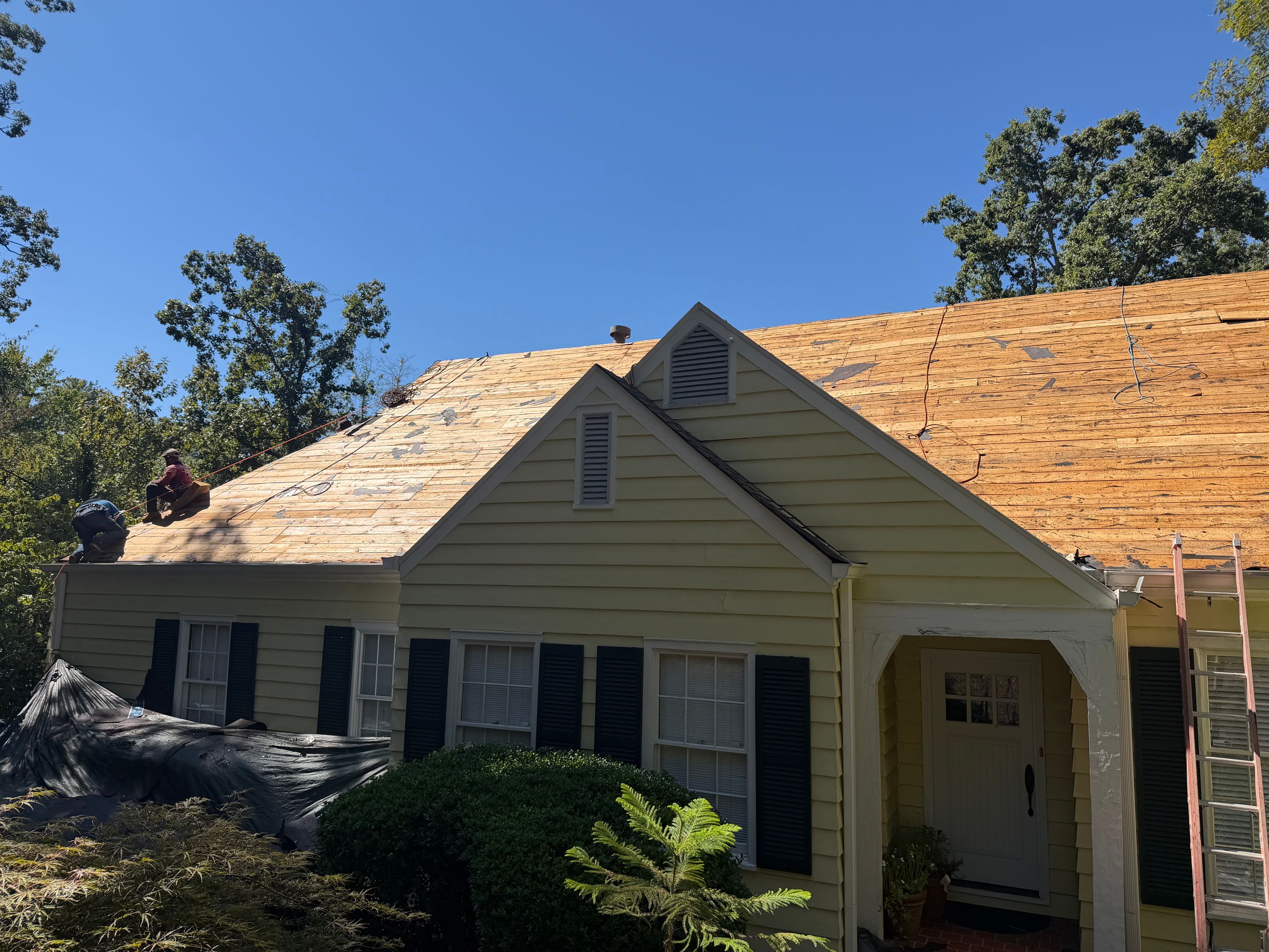 Exposed roof decking sits behind two yellow gables during a home improvement project in Mountain Brook.