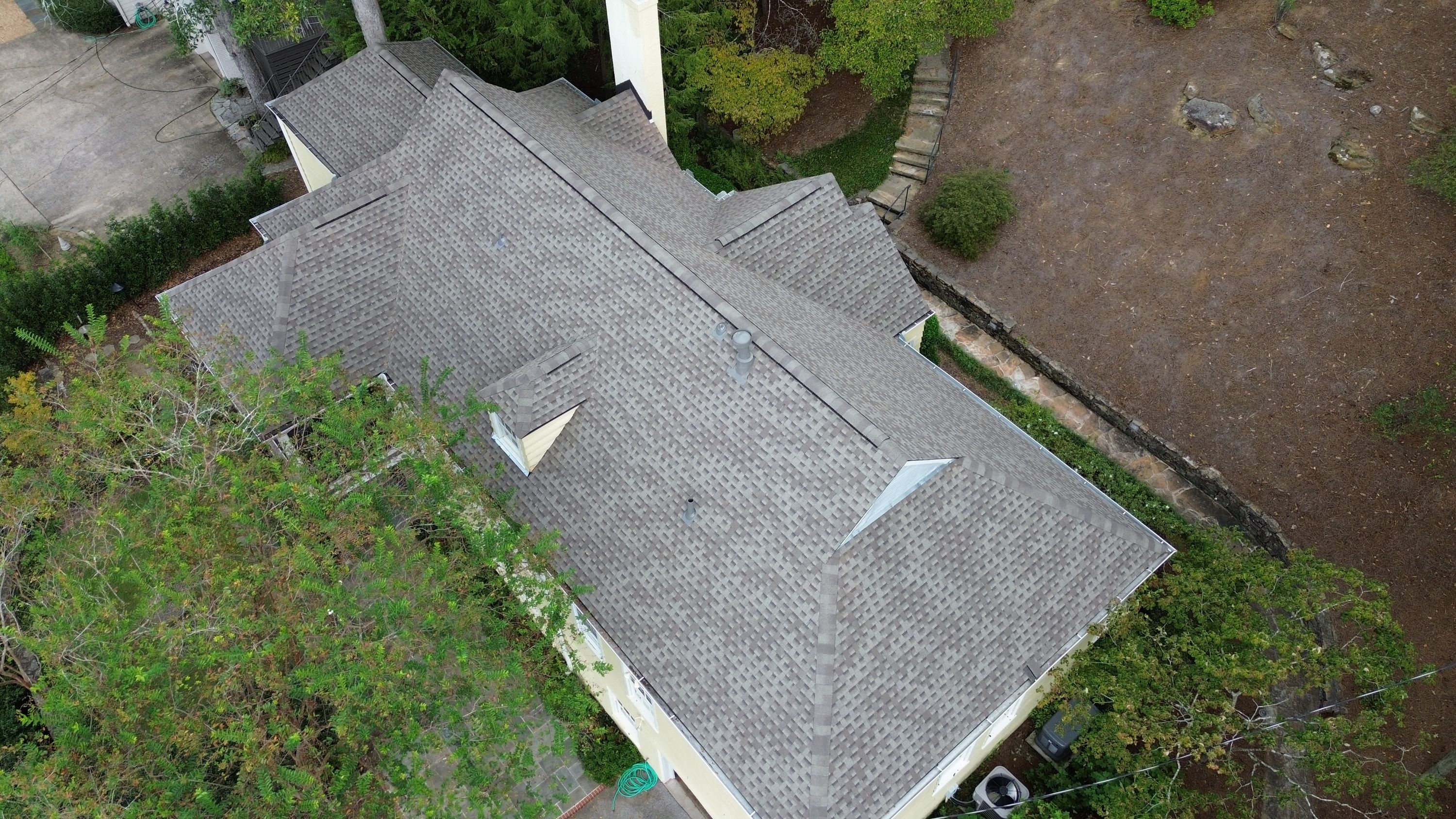 Two grey pipe vents protrude from a newly completed shingle roofing installation.