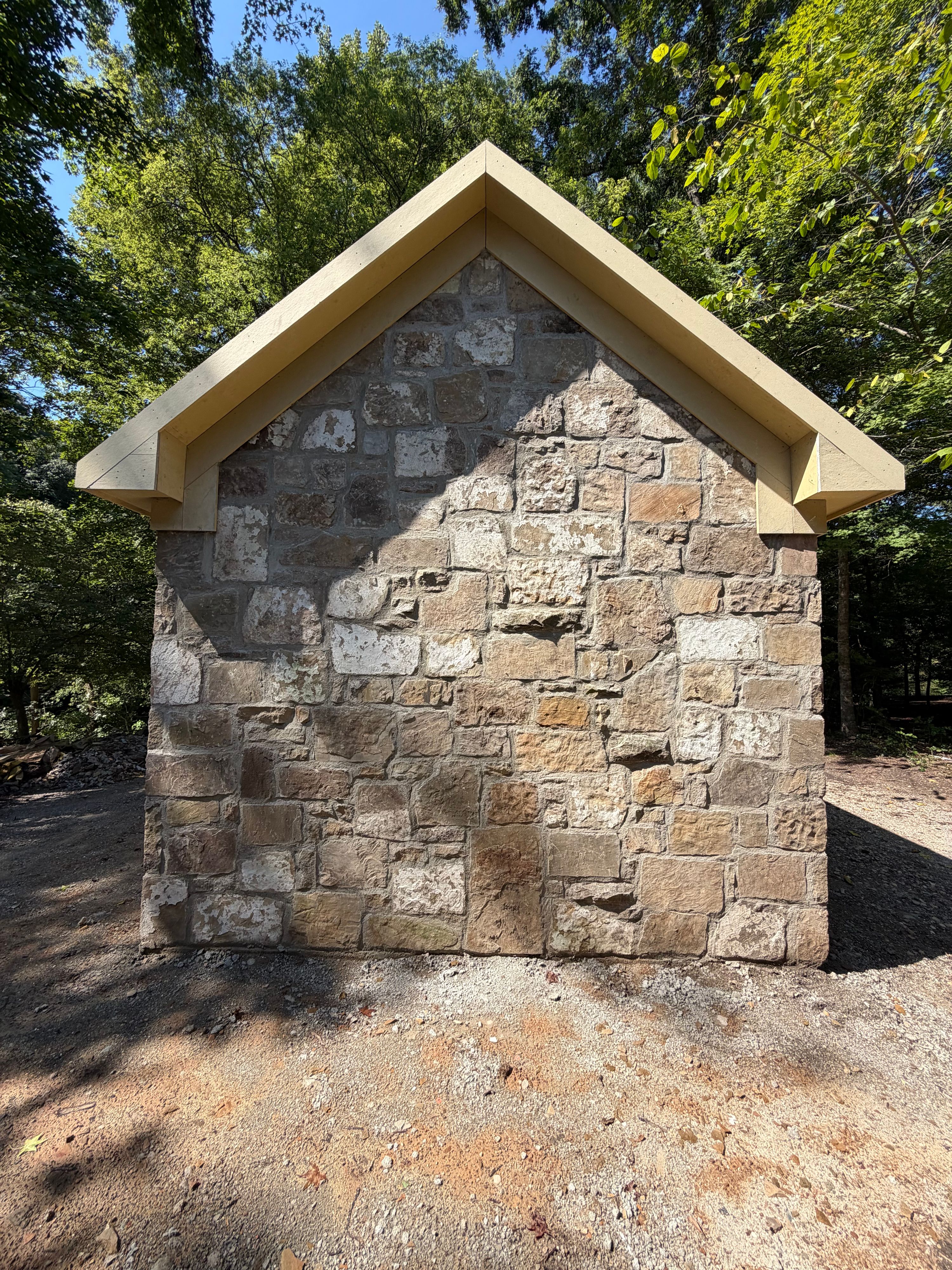 Gable end of the stone corn shed with wood fascia framed and awaiting its metal roof