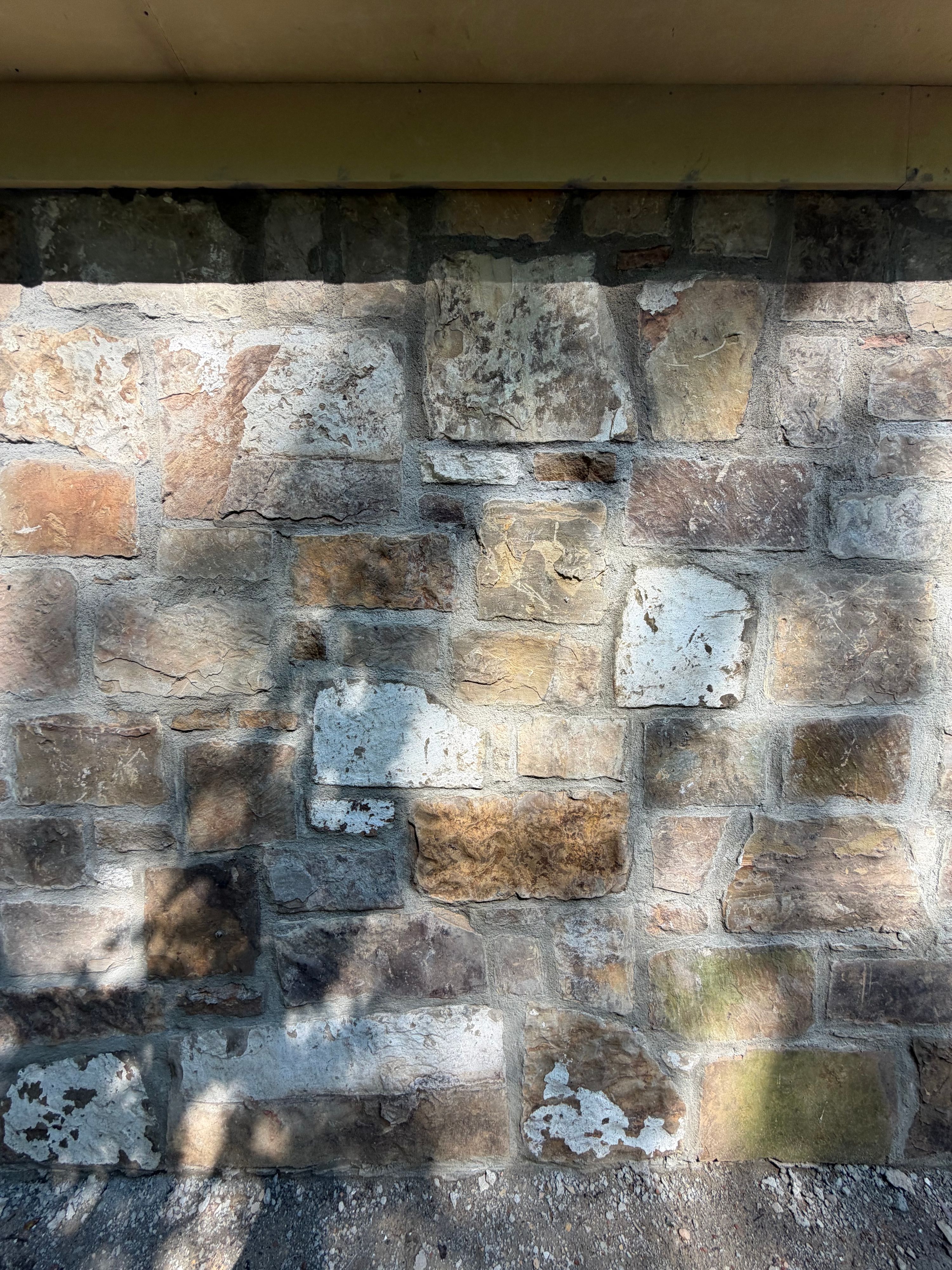 Close-up of salvaged rock with flecks of original paint and patina in the mortared wall