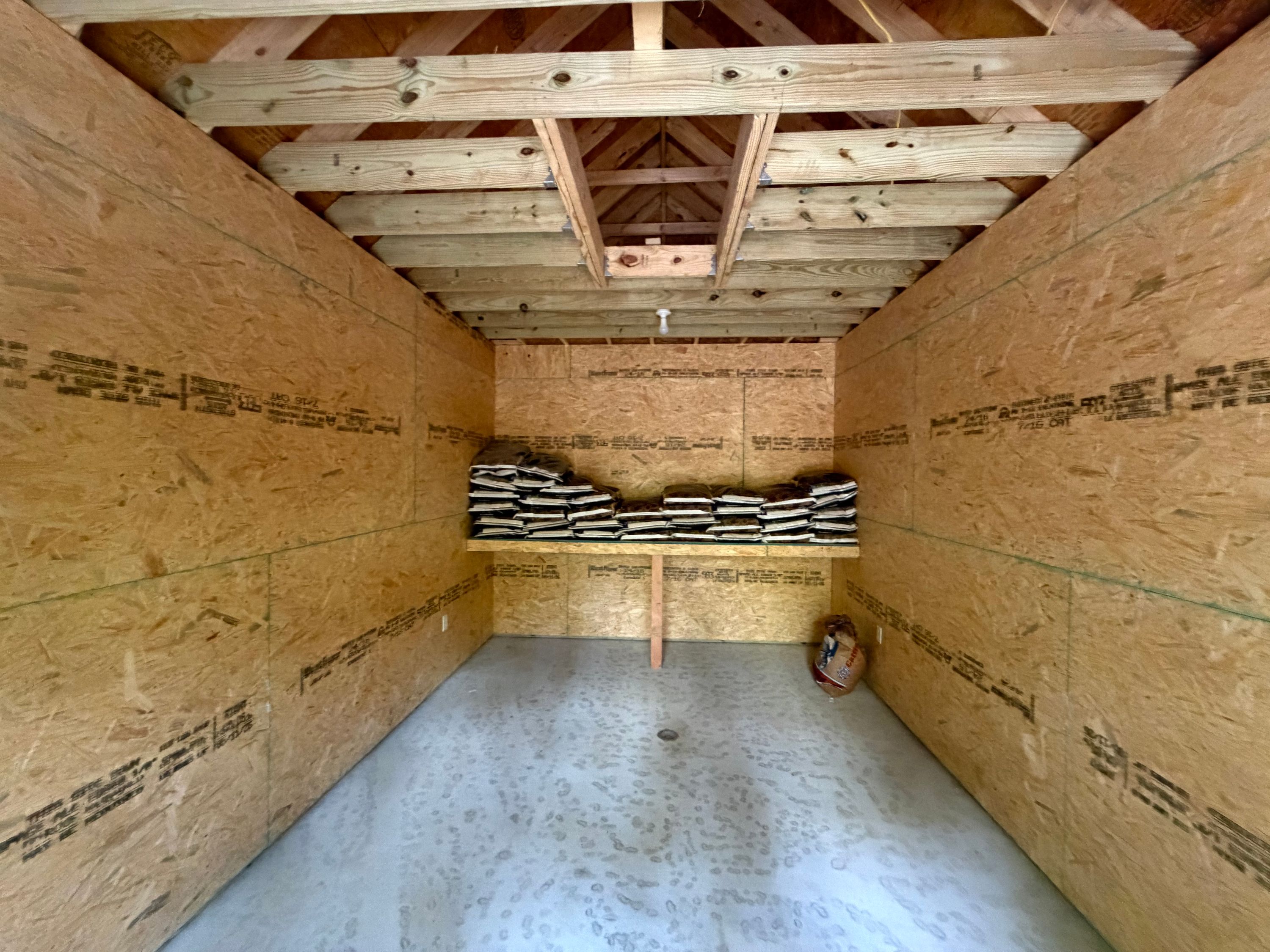 Exposed wood rafters and ceiling framing inside the newly constructed utility shed.