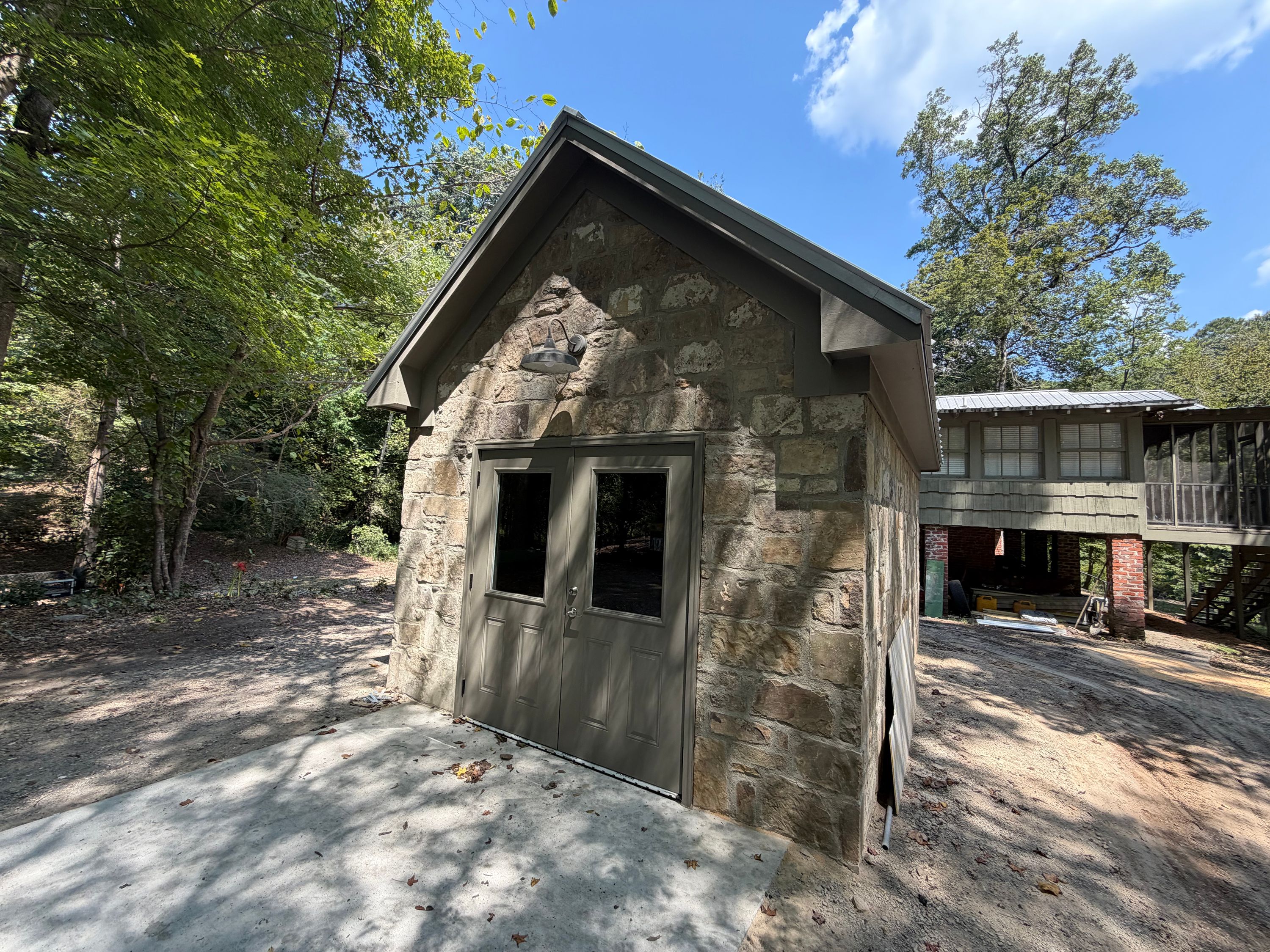 A freshly painted double door is nestled into the mortared stone wall beneath a clean gable roof.