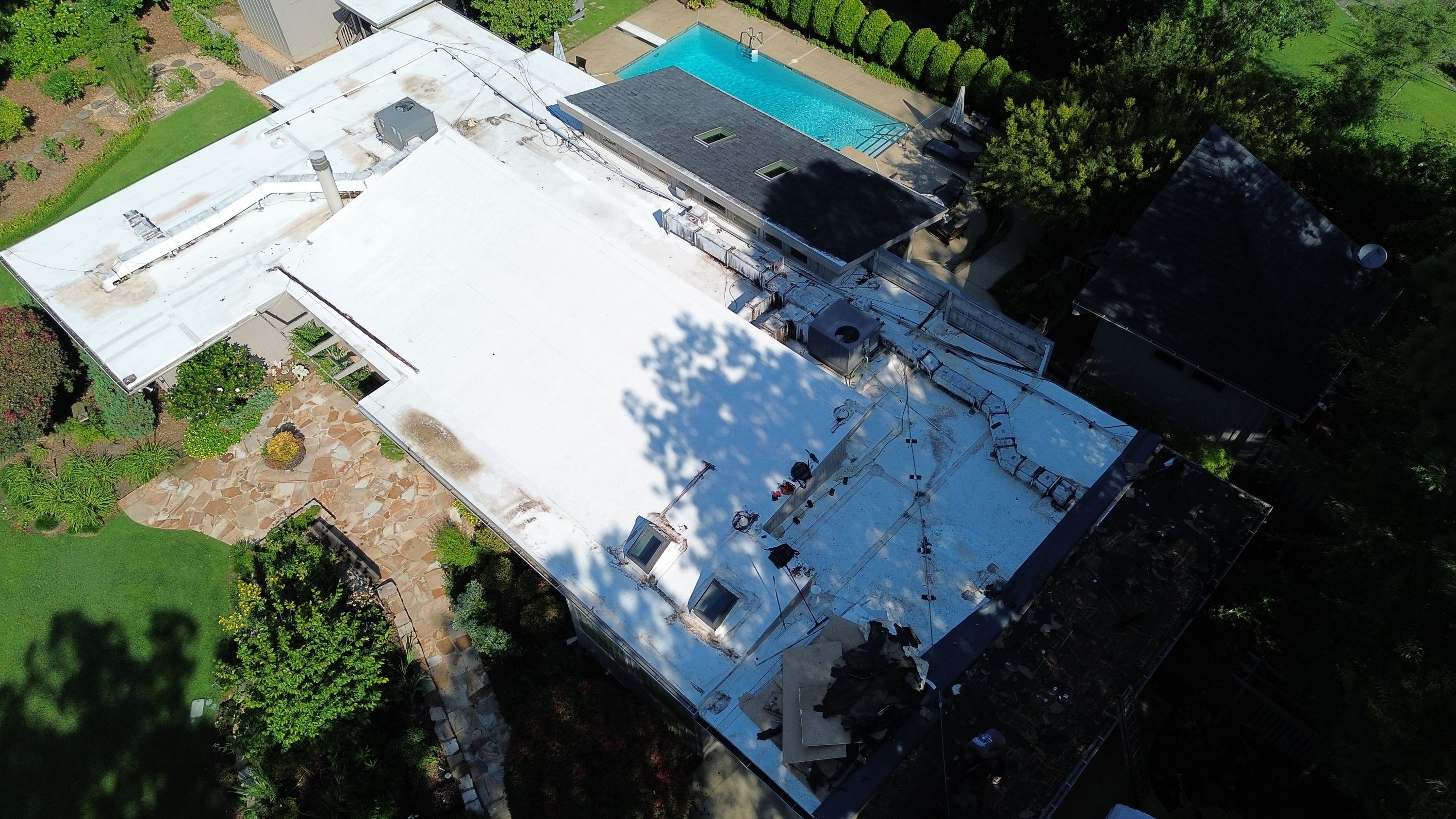 An overhead view reveals a white flat roofing installation near a dark shingle section in Mountain Brook.