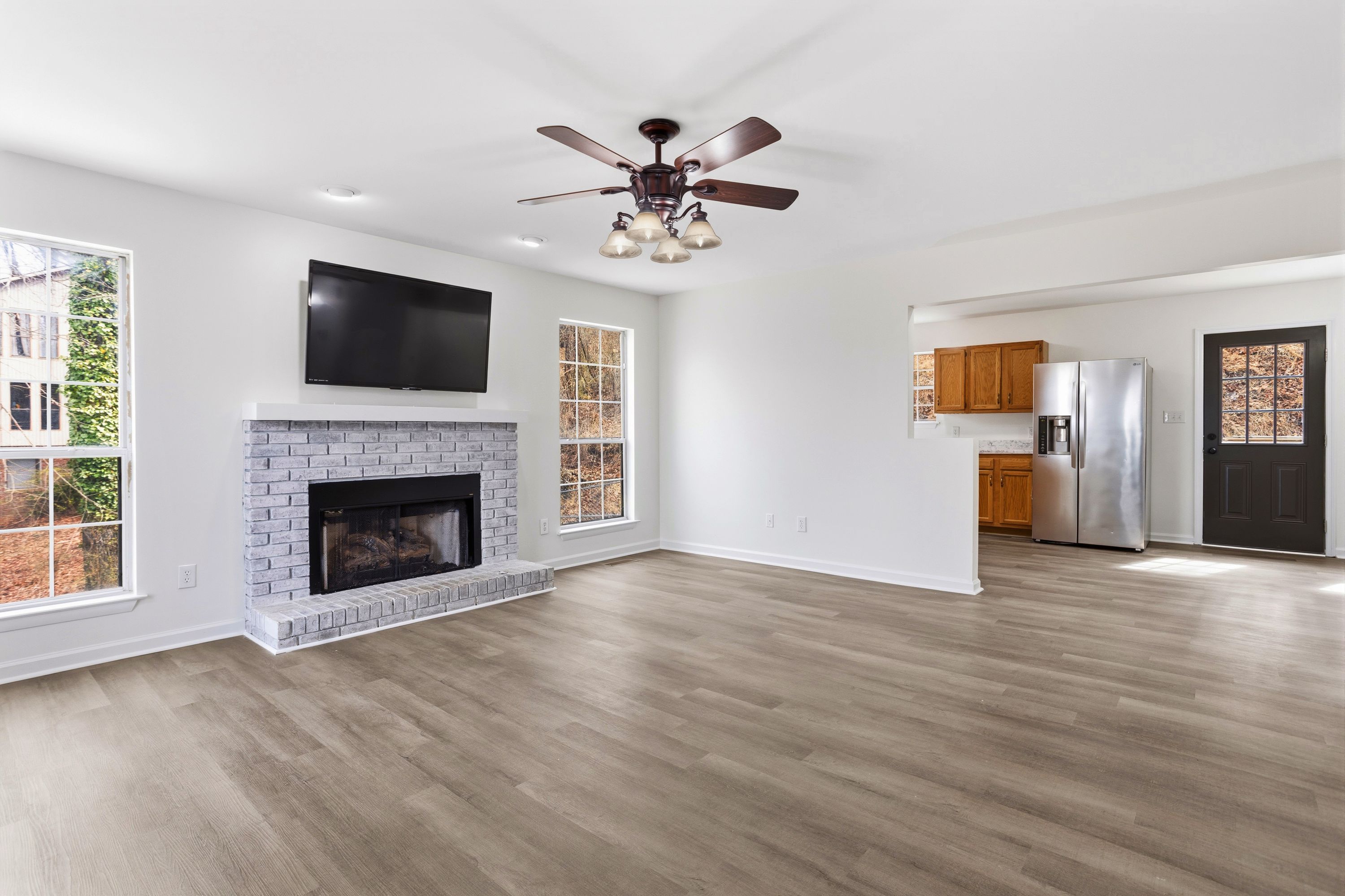 Bright living room with a grey brick fireplace inside a Leeds, Alabama residence recently updated with a new roof.