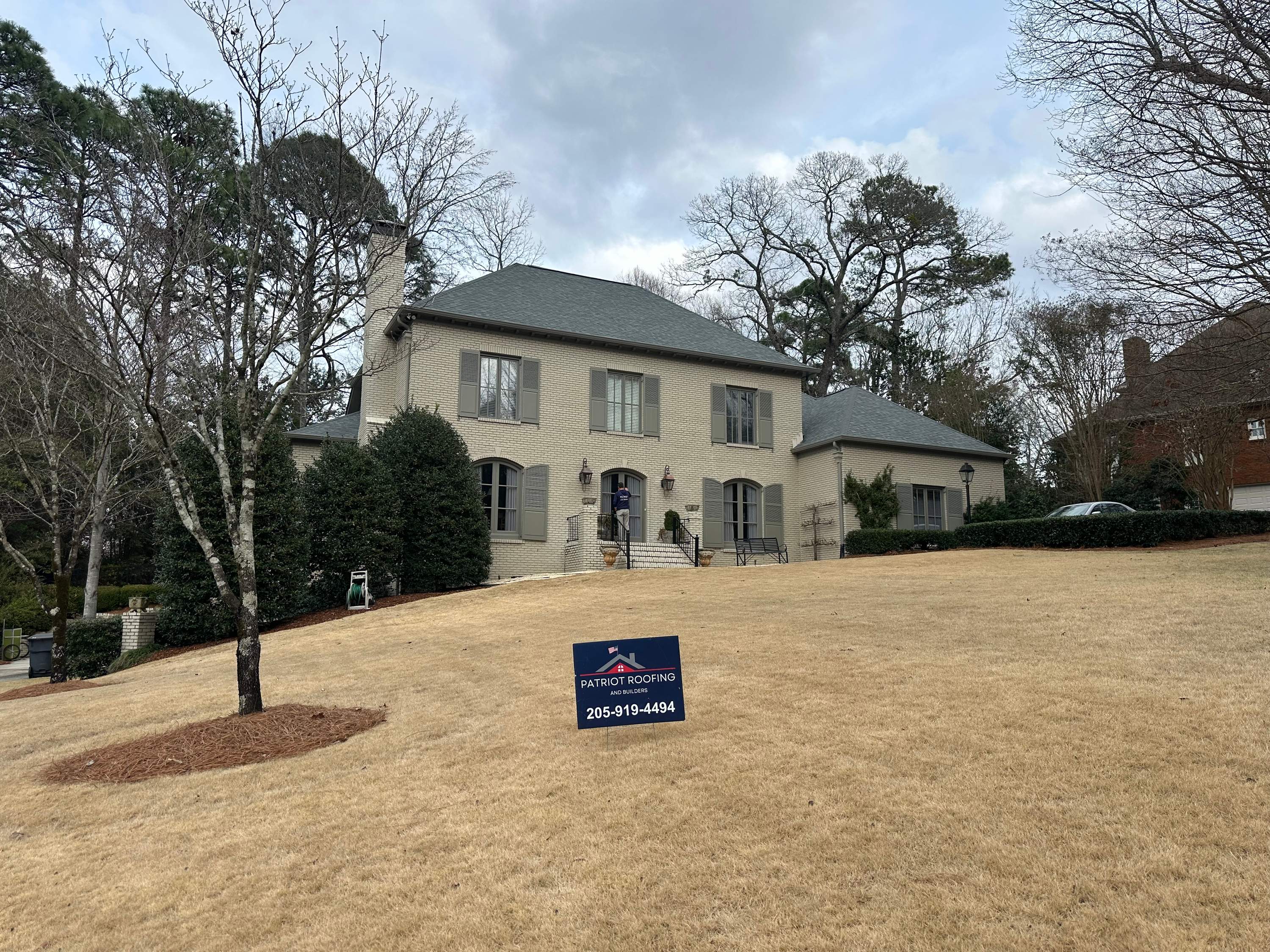 Front view of a stately Vestavia Hills home featuring a professional roof replacement by Patriot Roofing and Builders.