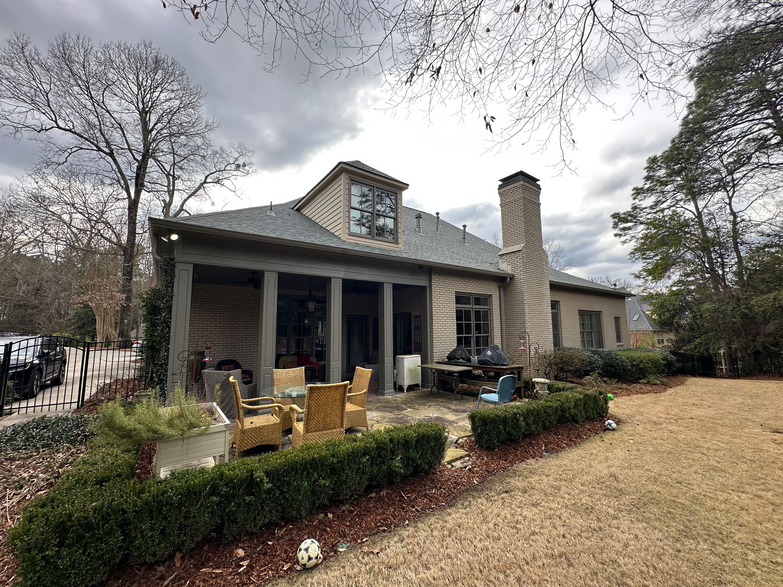 Rear view of a home in Vestavia Hills showing a high-quality roof replacement over the patio and chimney area.