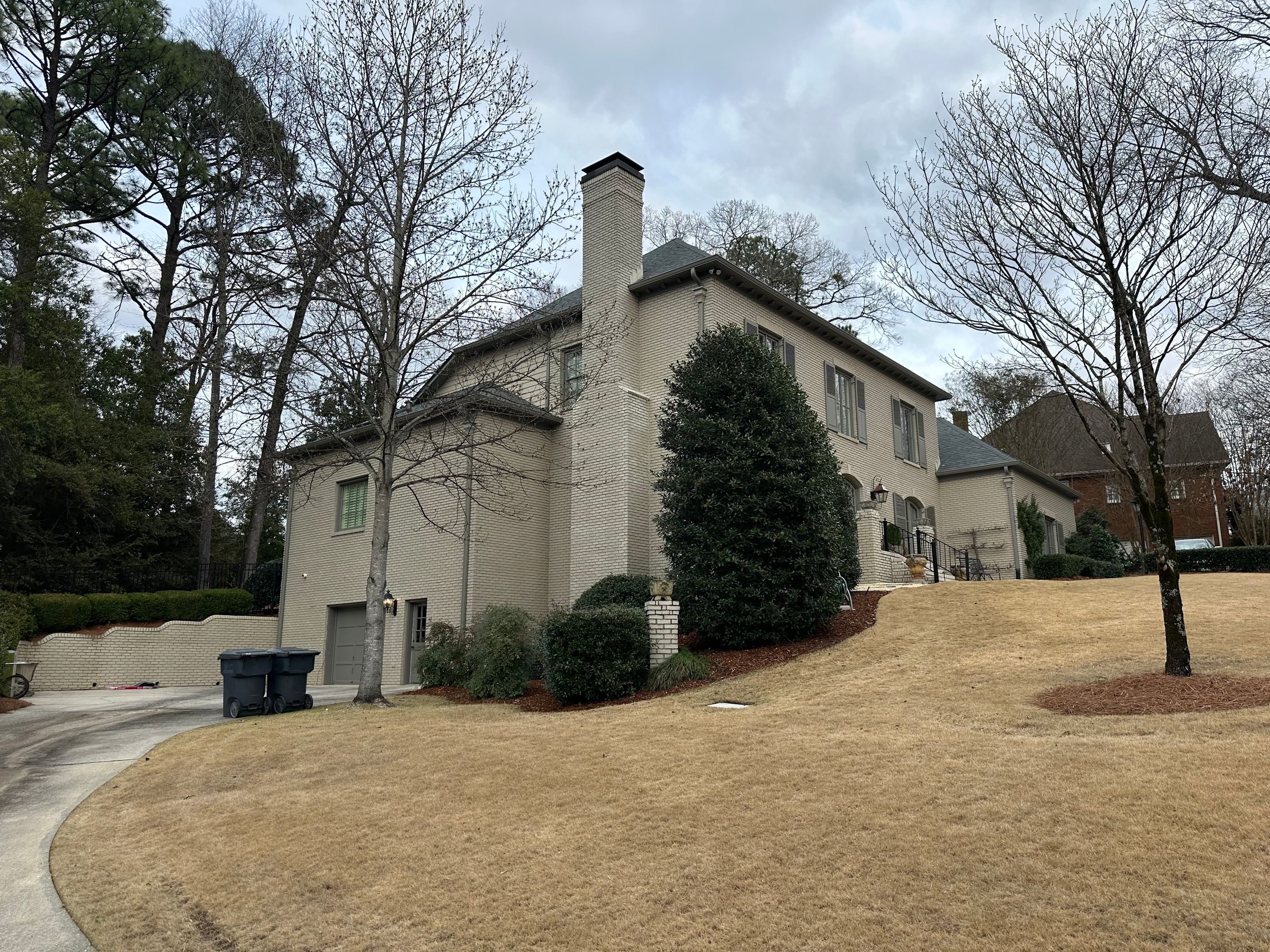 Side profile of a large brick residence in Vestavia Hills after a complete residential roof replacement service.