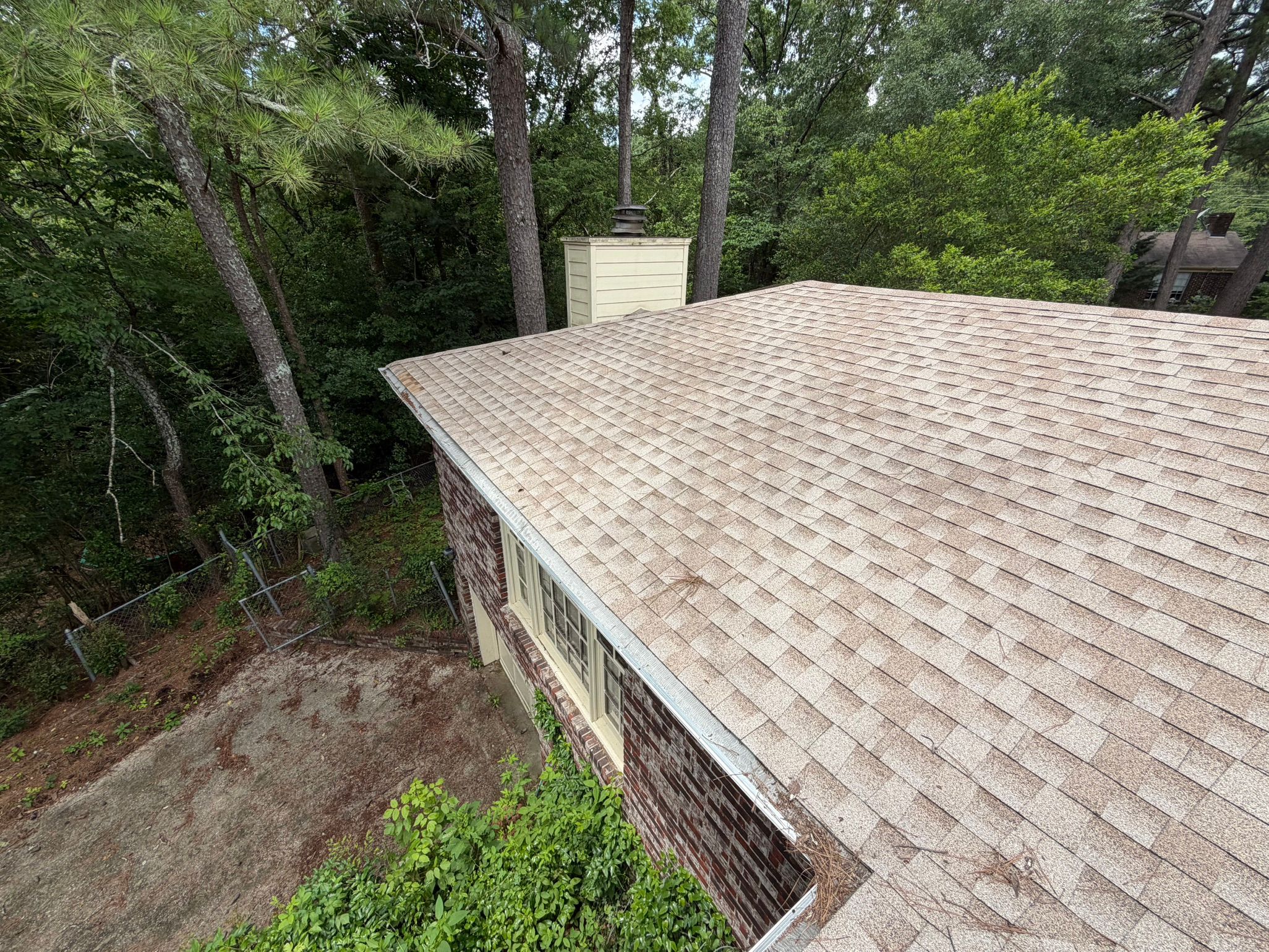 High-angle view shows clean gutter guards lining a completed shingle roof plane in Leeds.