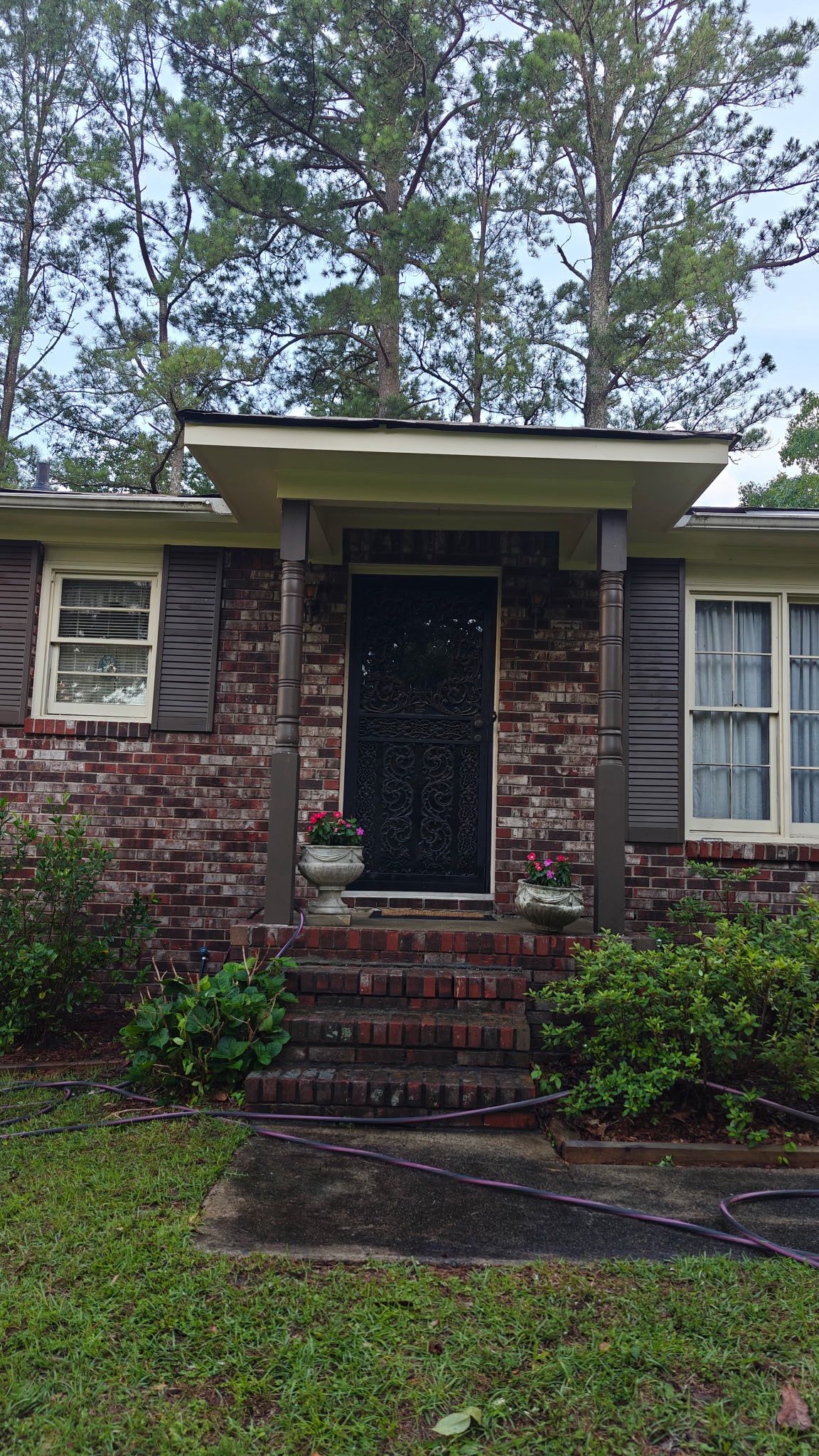Completed soffit and fascia repairs show a clean cream-colored finish above the brick entryway.