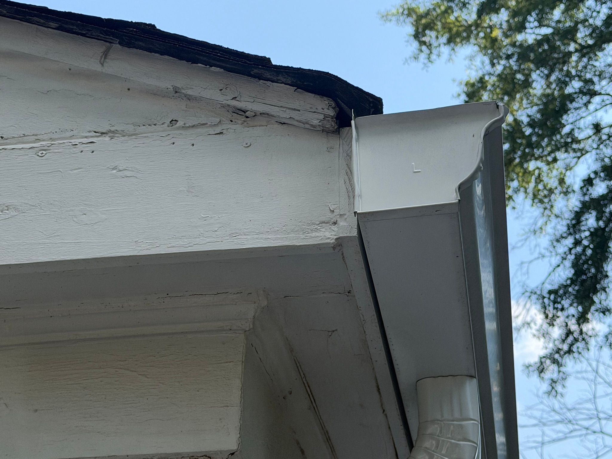 Water damage decays the fascia board and peeling paint at this roof junction in Brookwood Forest.