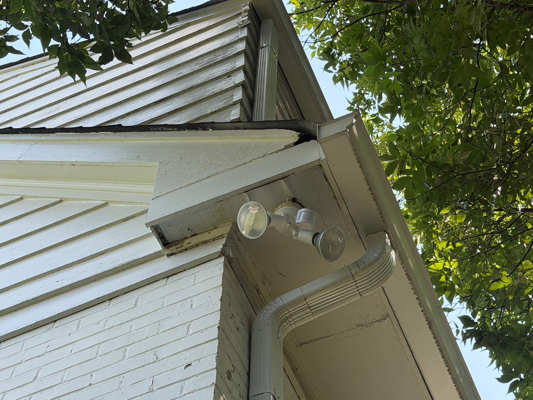 Exterior house trim shows signs of water damage near the gutter line before a roof repair.