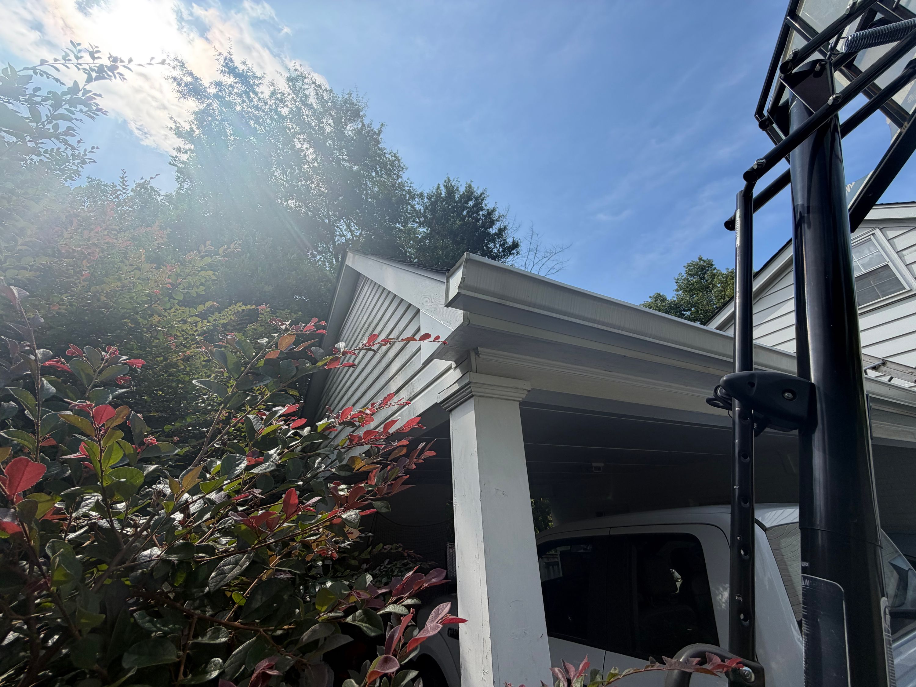 Wood trim meets a white porch column below the roofline, showing areas prepped for roof repair.