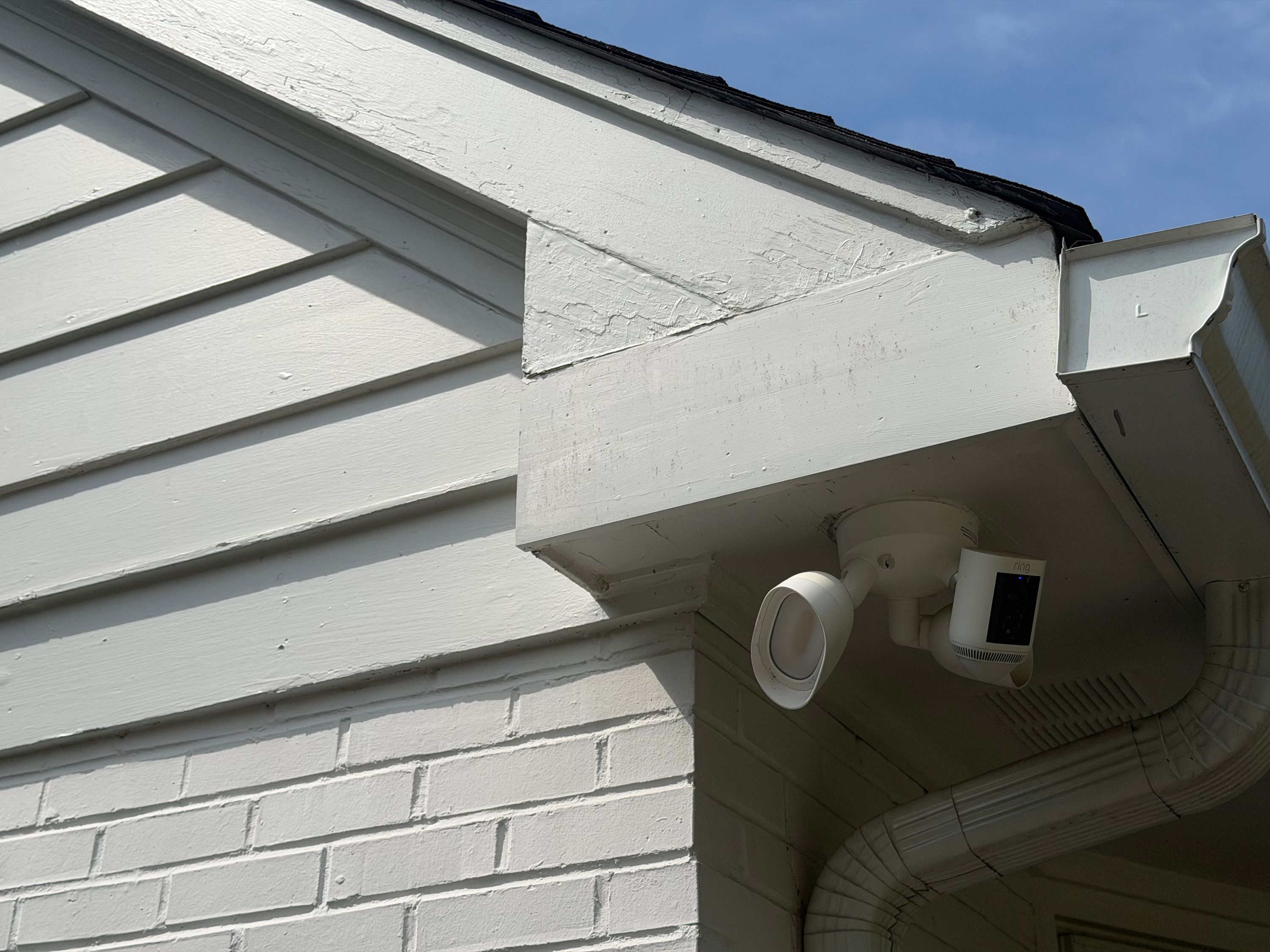 Peeling paint on the exterior wood trim above painted brick siding indicates water infiltration.