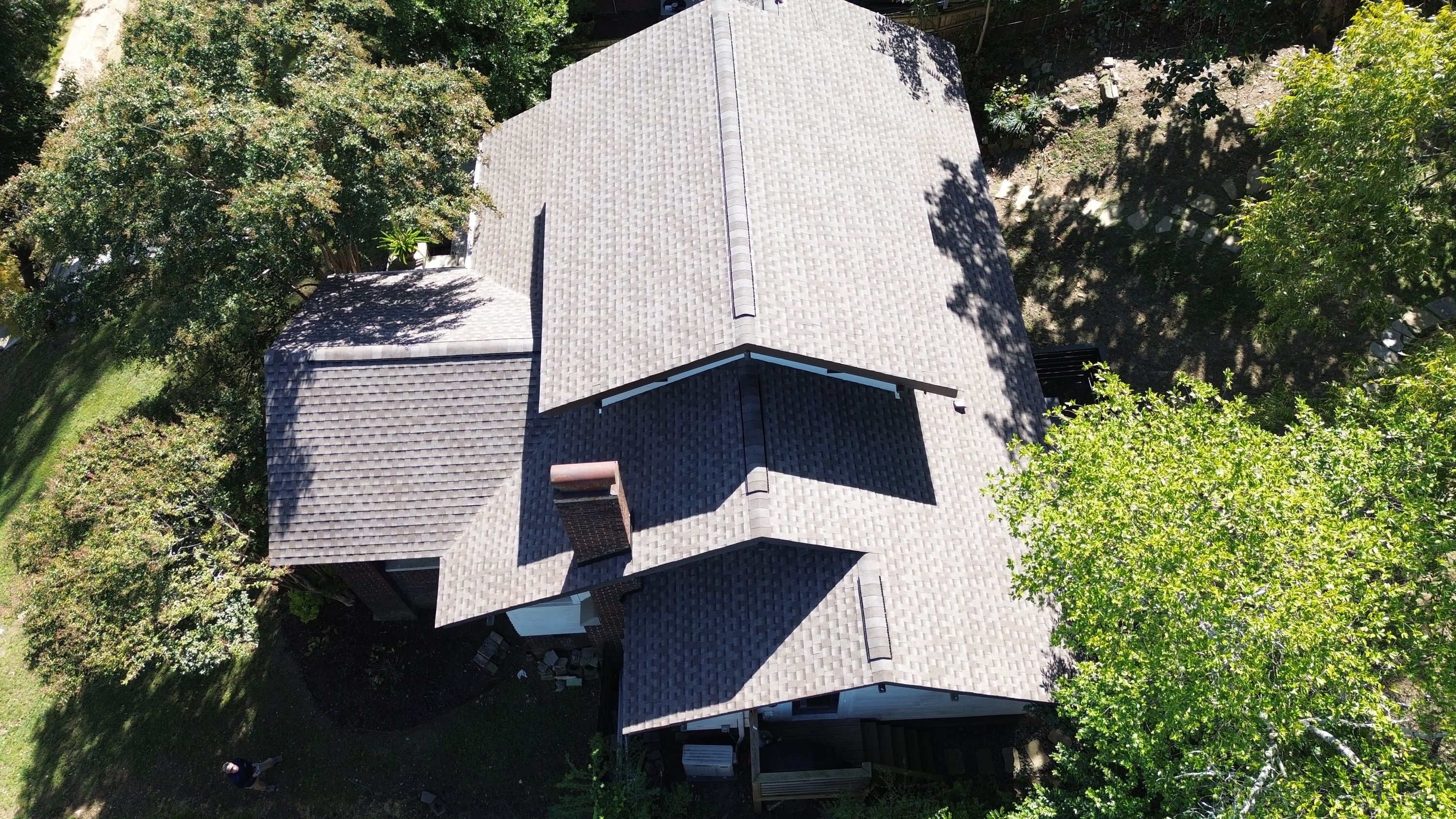 Stepped gable roof planes with fresh architectural shingles, white gable siding, and dark fascia above the back deck.