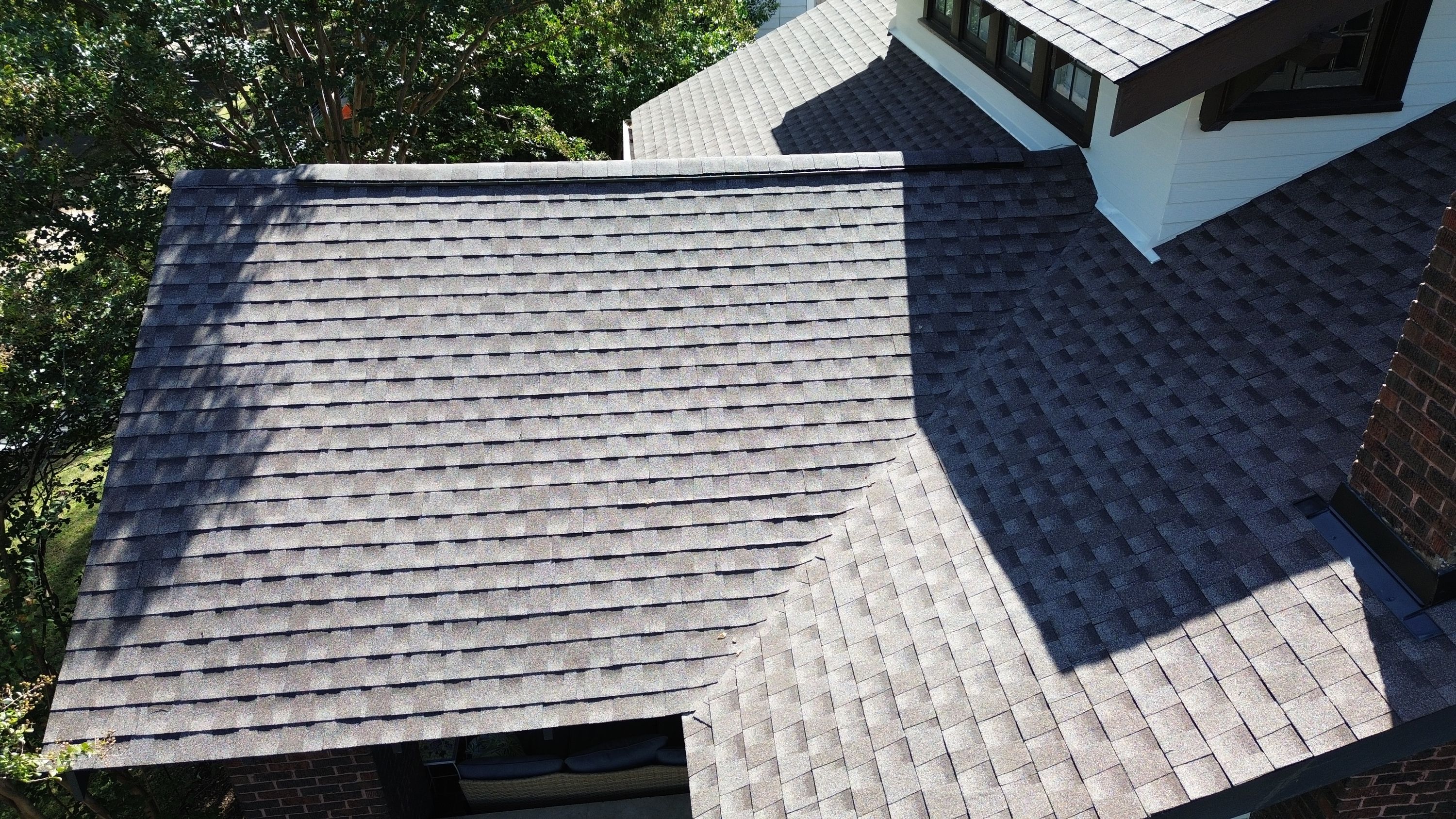 Closed-cut valley where two architectural shingle roof planes meet below a capped ridge line in Forest Park.