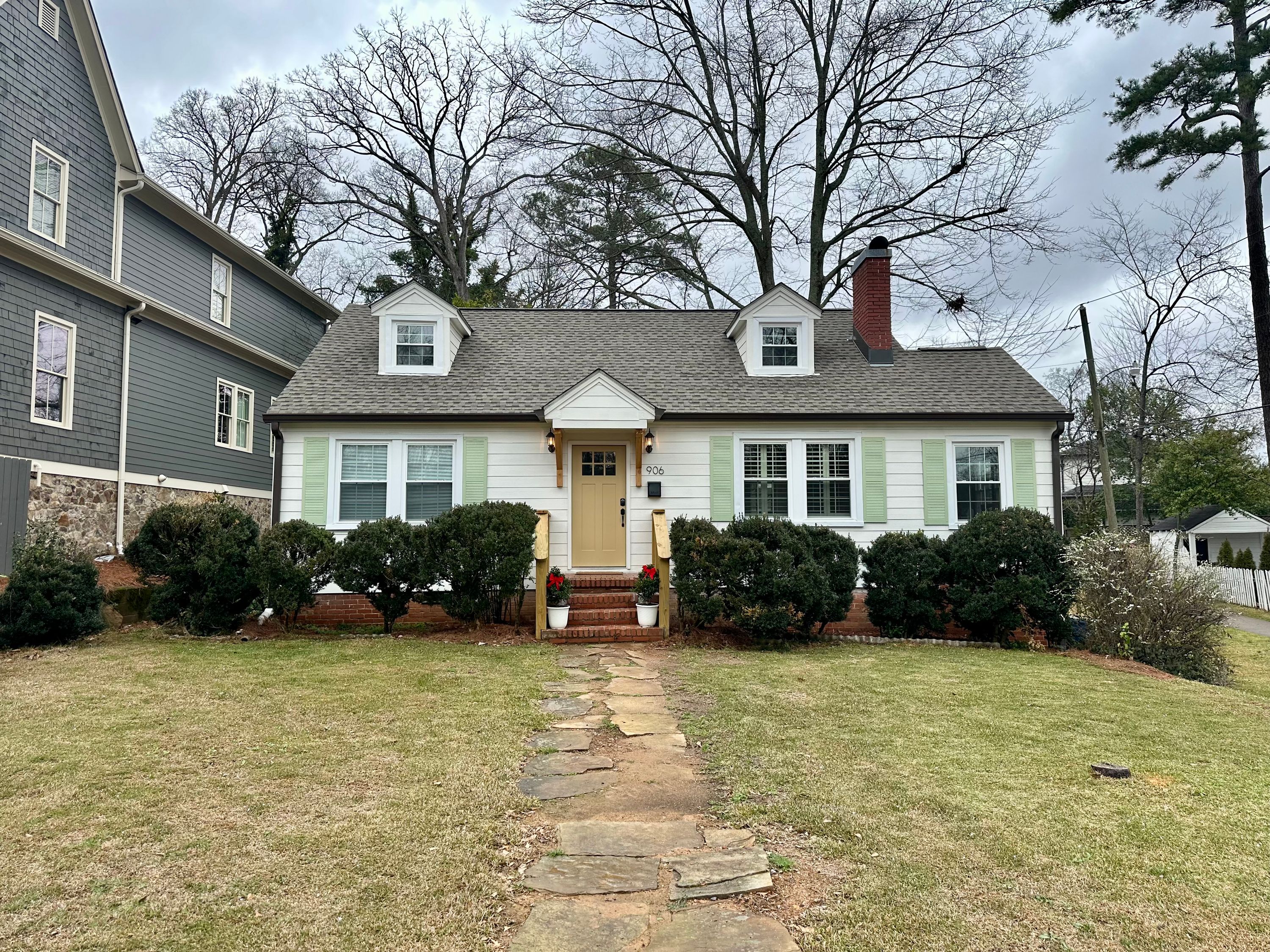 Exterior of a white cottage in Homewood featuring new roof shingles and updated replacement windows.