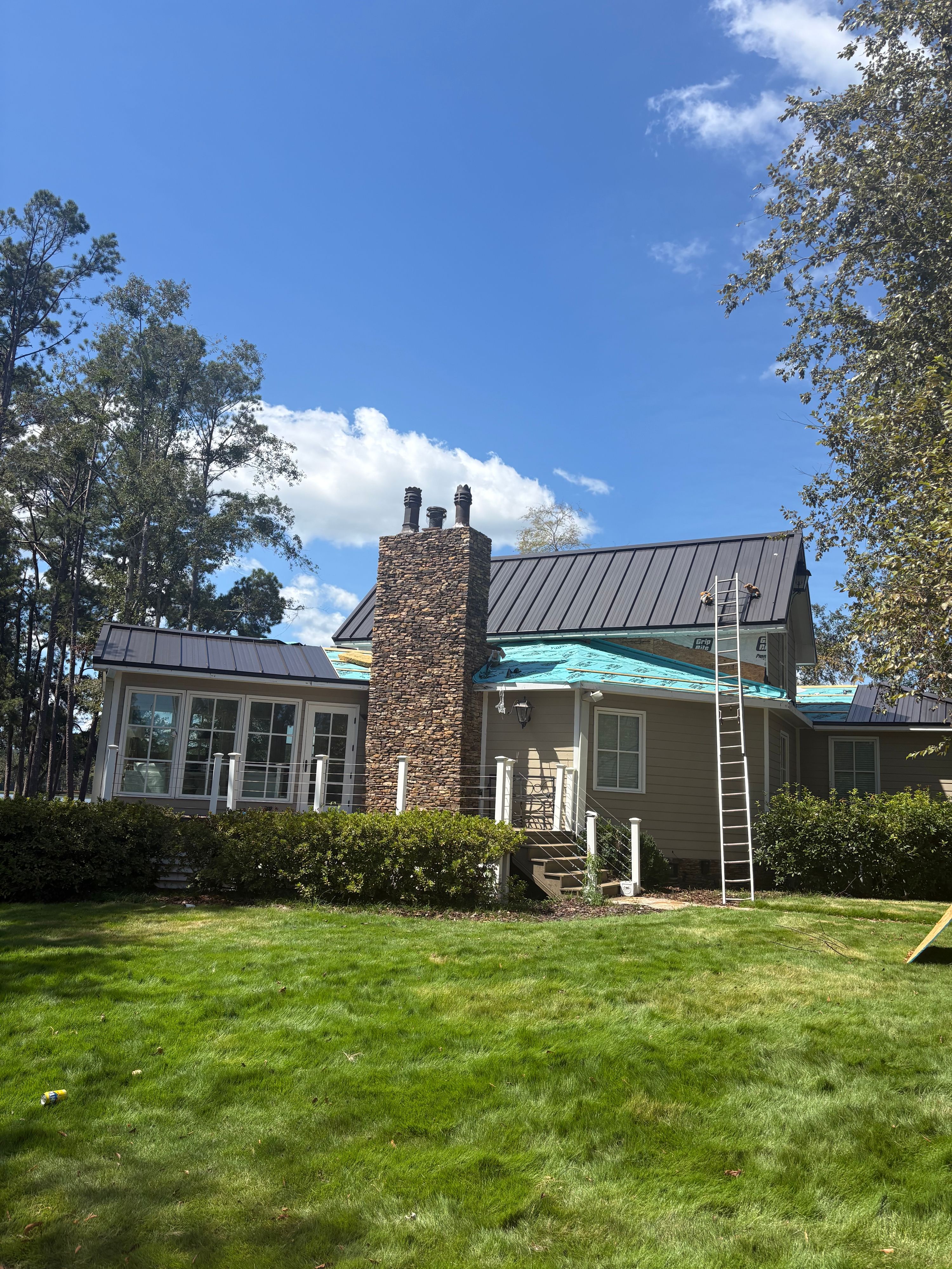 Installers prep for a metal roofing upgrade around a stone chimney during this Birmingham home renovation.