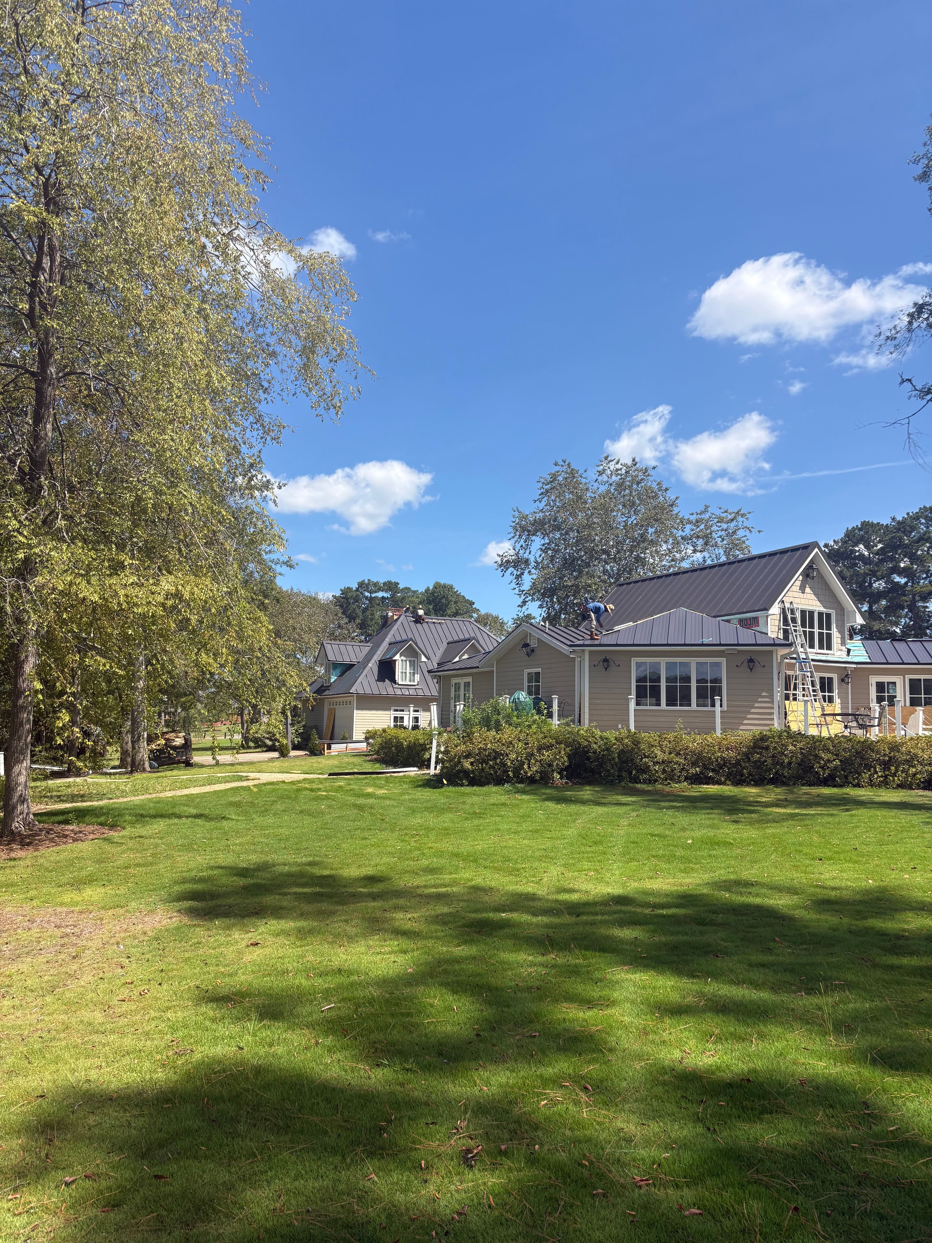 Multiple gables showcase the sleek lines of a completed metal roof installation on a lakeside residence.