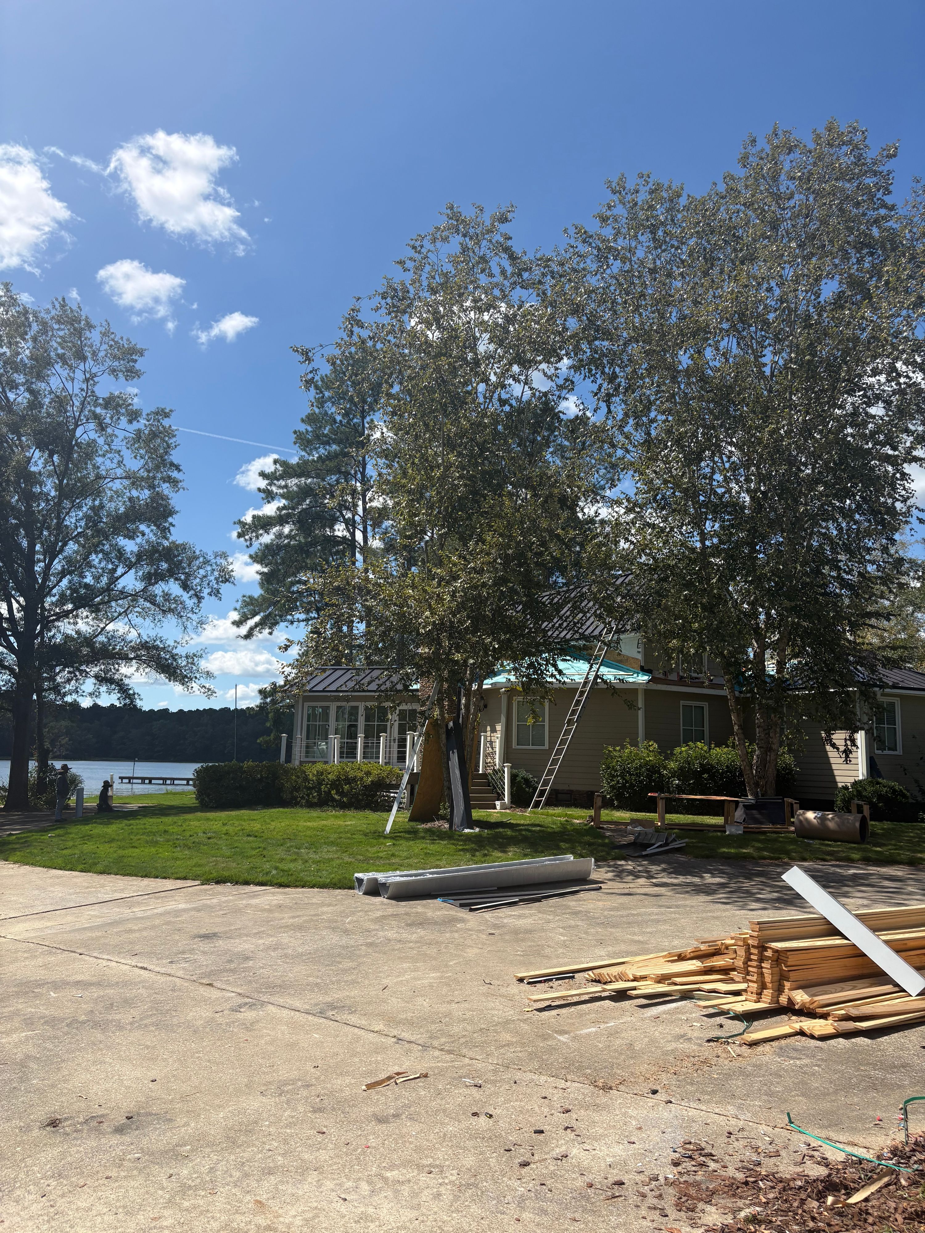 New metal roofing components and materials sit on the driveway during a residential roof replacement.