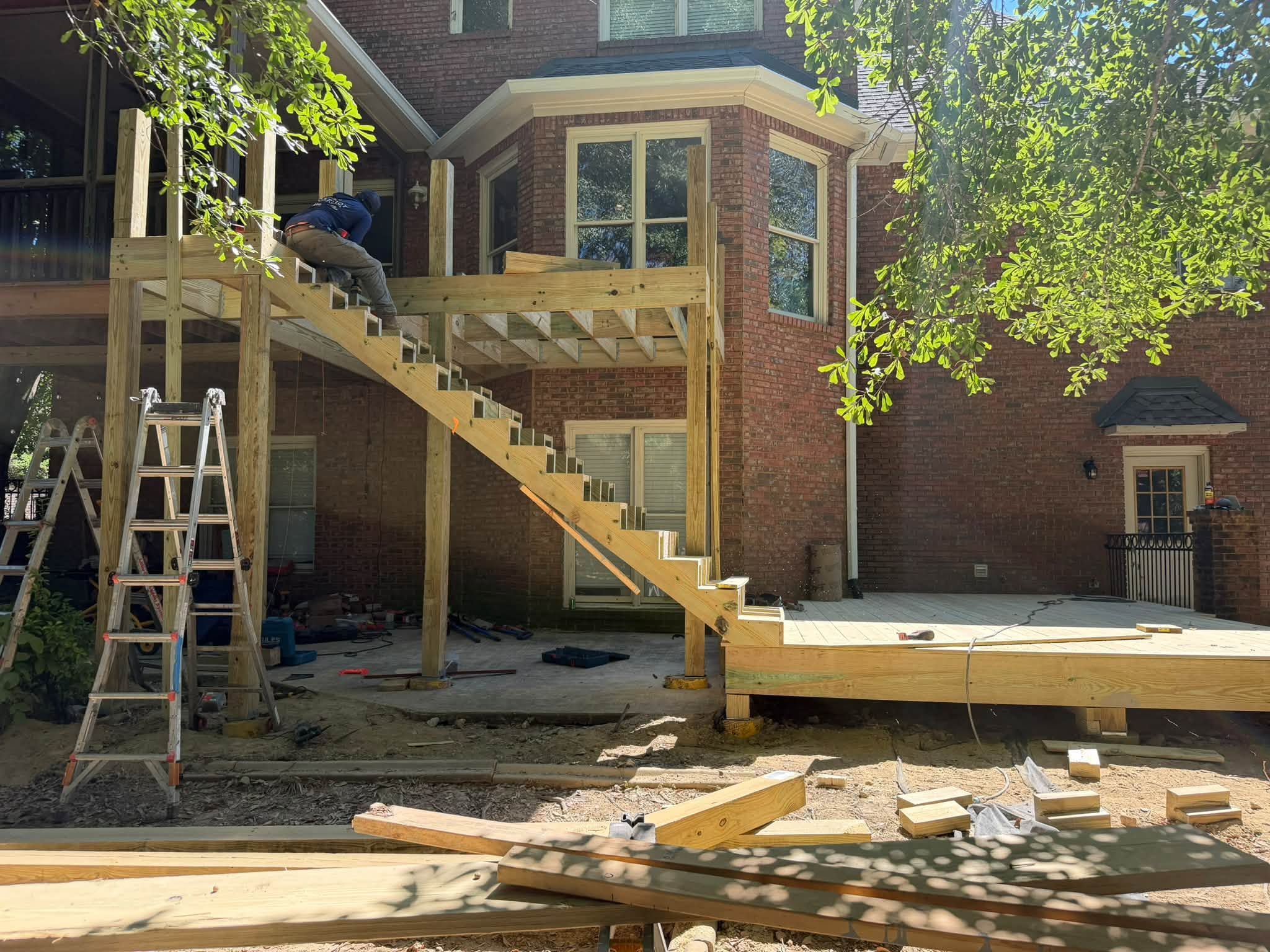 Structural floor joists and stair stringers span the upper level of a custom deck build.