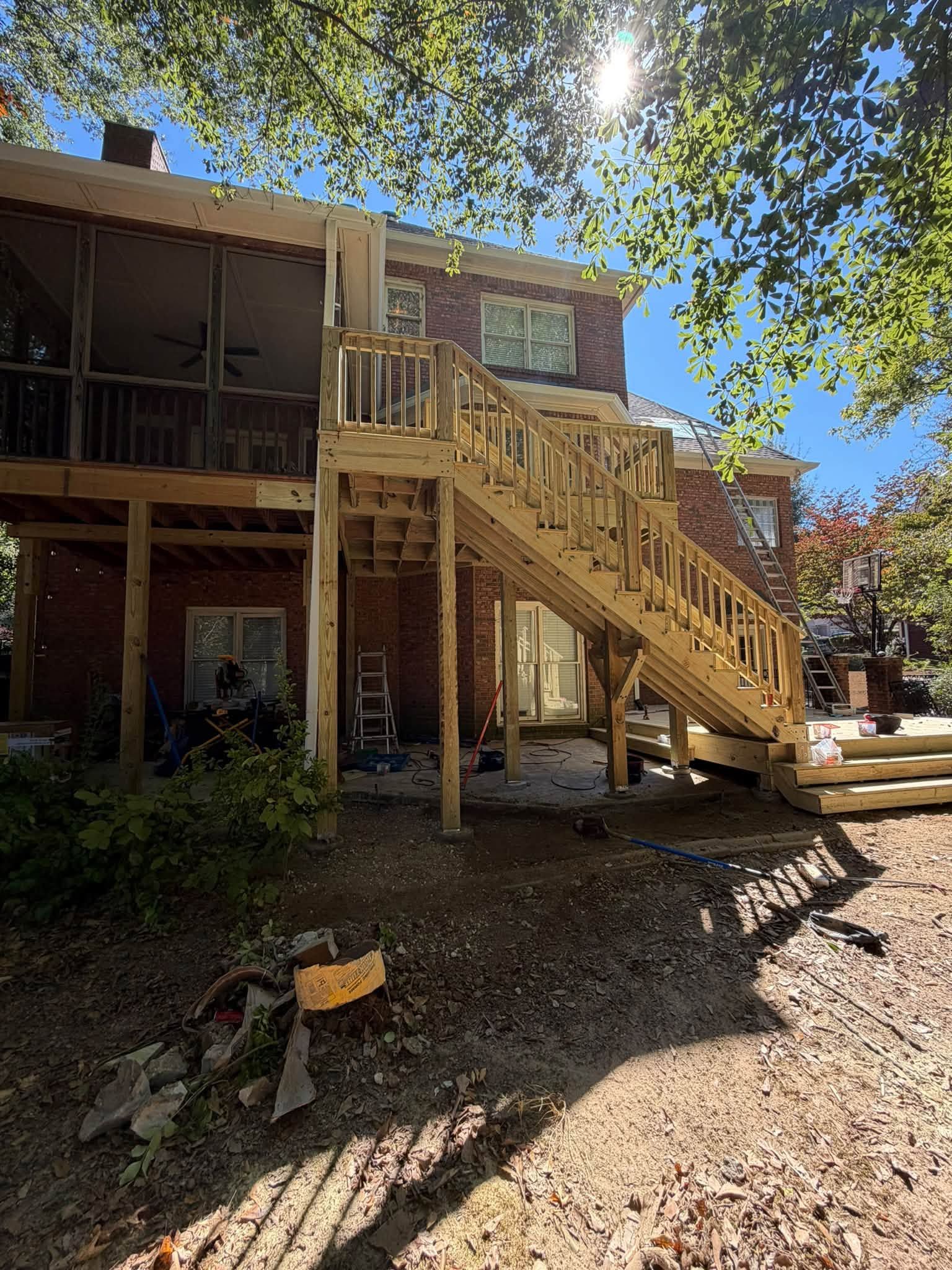 Wooden balusters and handrails align along the rising staircase of a multi-level deck.
