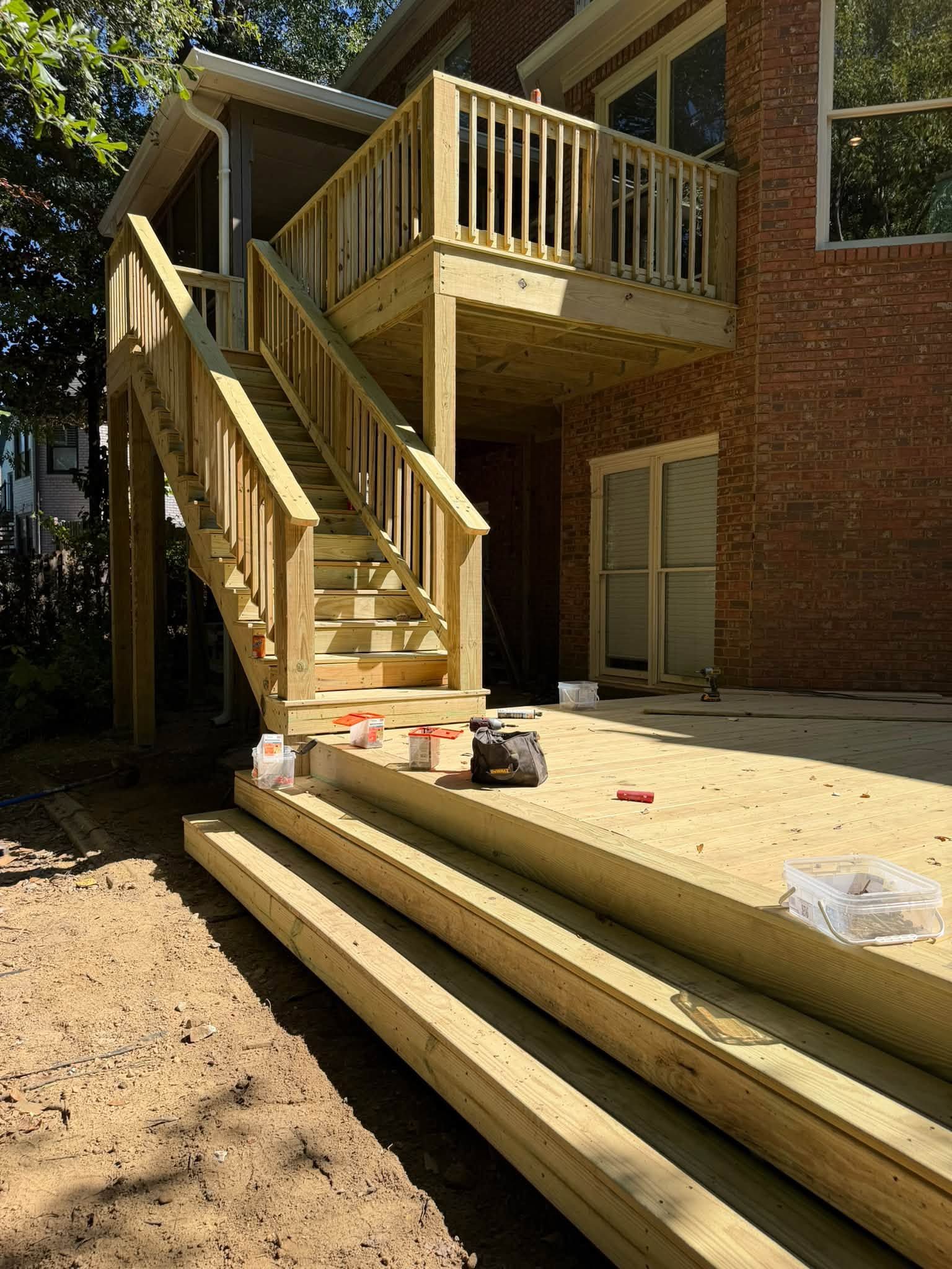 Wide wooden steps wrap around the base platform connecting the upper staircase to the ground level.