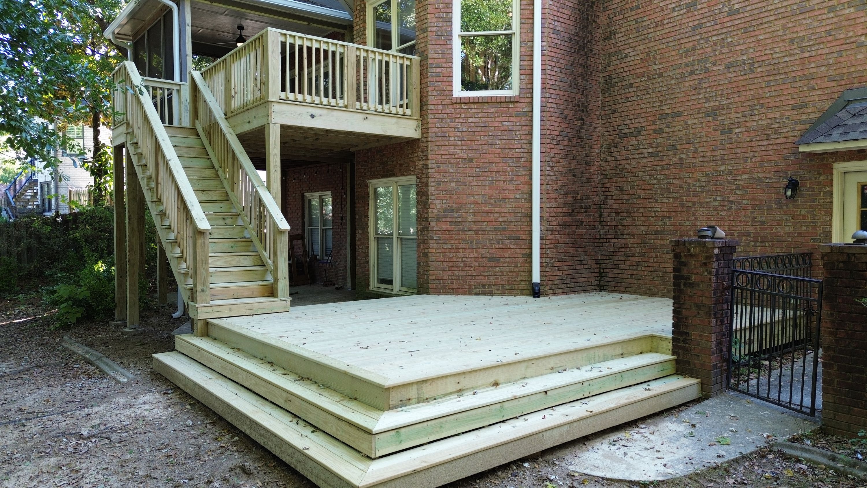 A custom deck build in Windchase features fresh wooden surface boards adjacent to a brick home exterior.