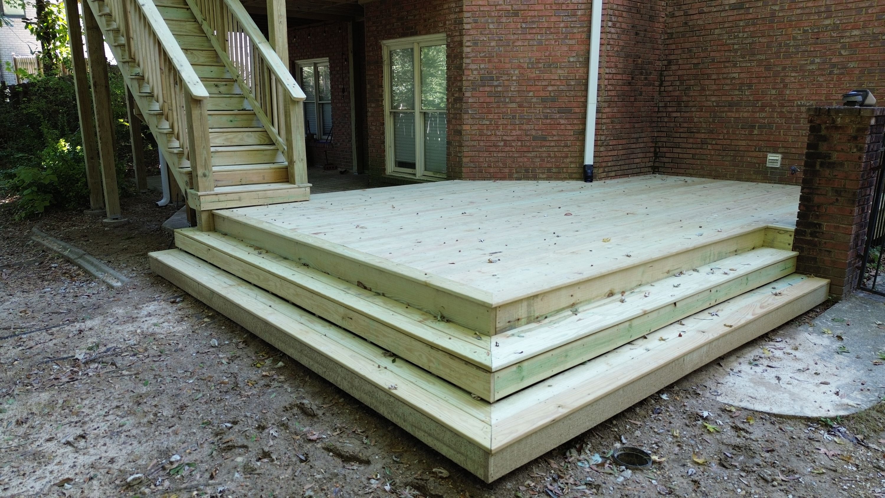 Corner view of multi-level step treads transitioning down from the lower platform to ground level.