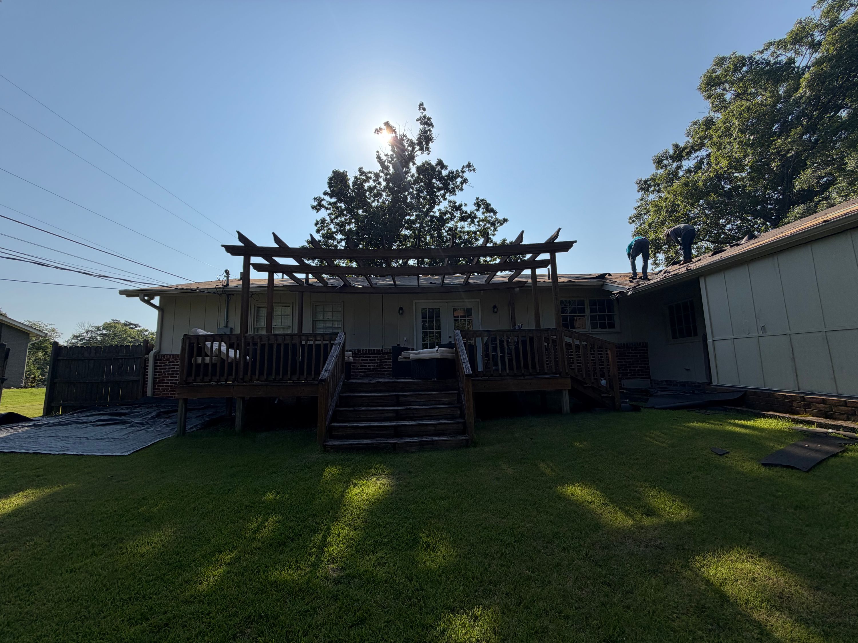 An existing wooden deck and overhead pergola frame the back of a house during a Gentilly Forest home update.