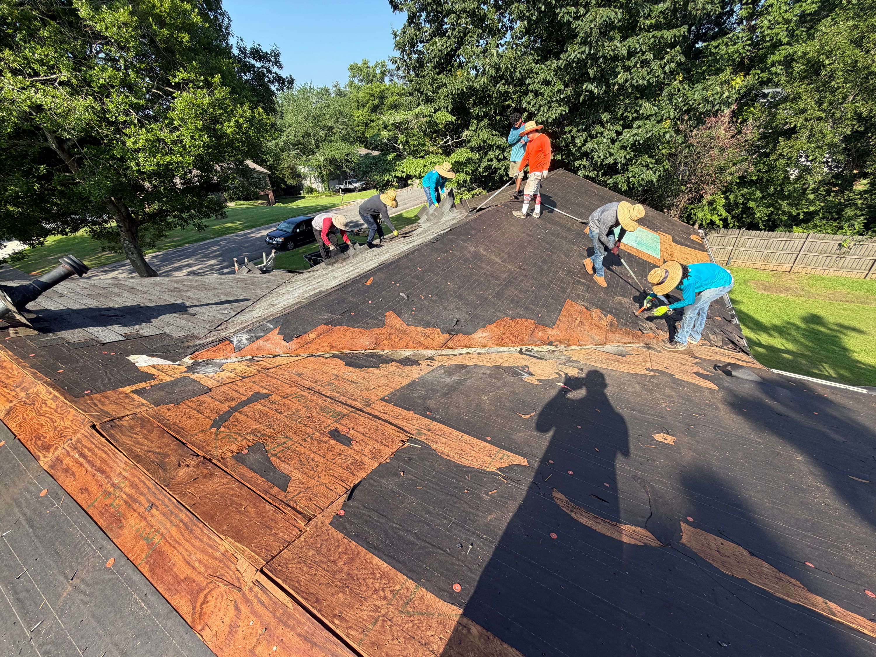 Old shingles are scraped away, exposing underlayment and plywood decking during a Columbiana Road roof replacement.