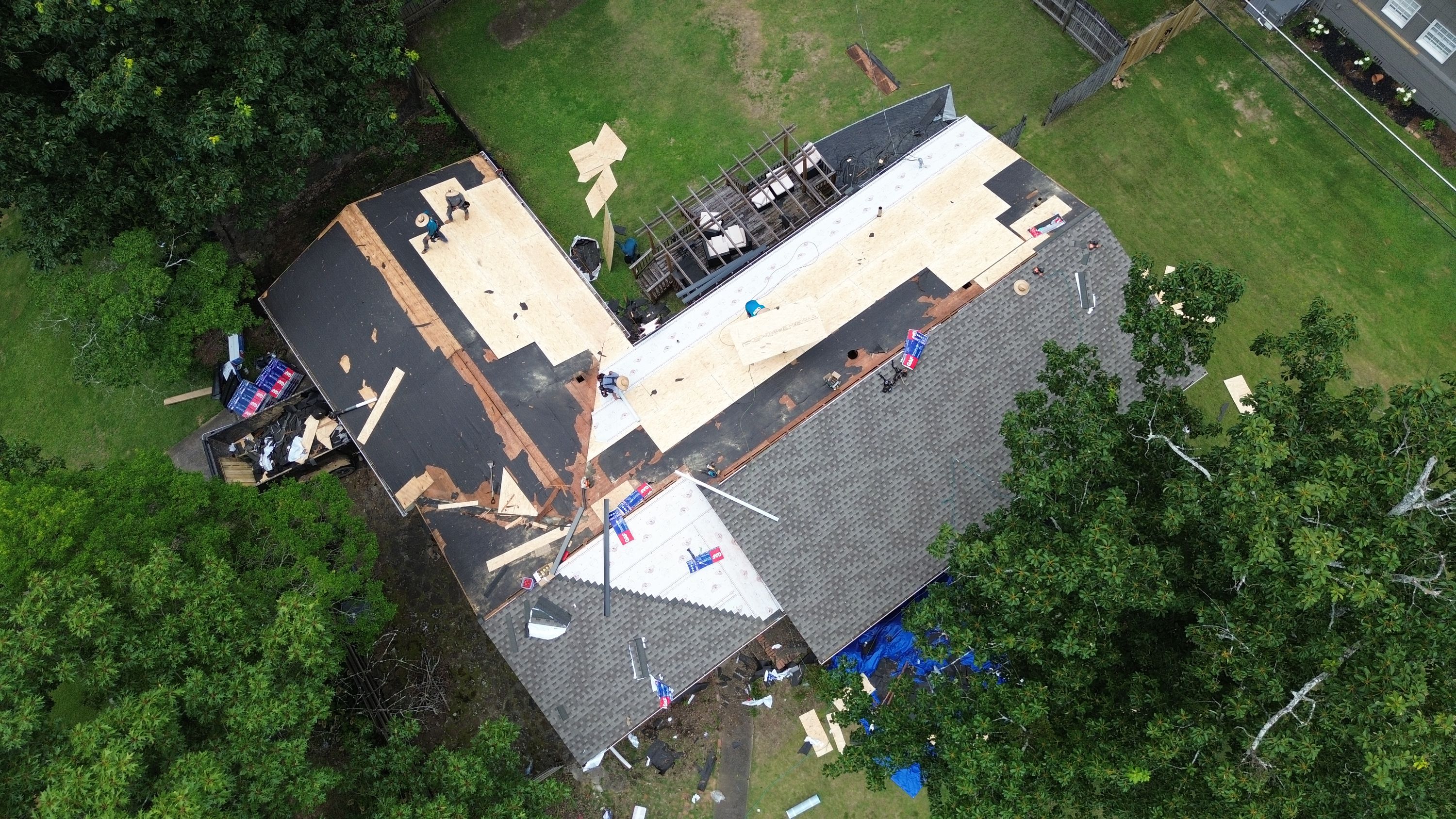 Overhead drone view shows a home receiving new roof shingles, underlayment, and decking on Columbiana Road.