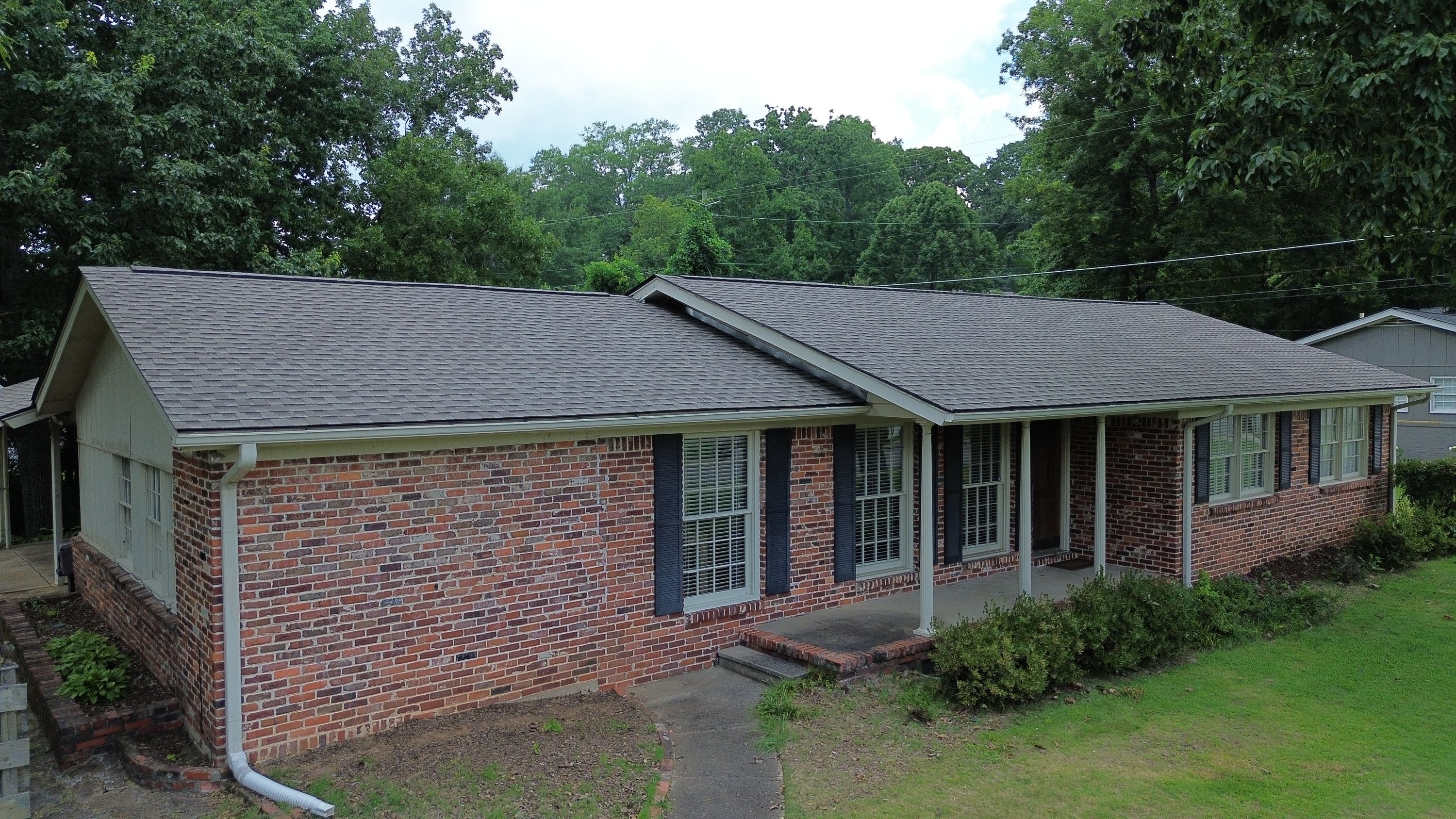 Close view of the newly installed dark grey shingle roof valley and gables on this brick home.