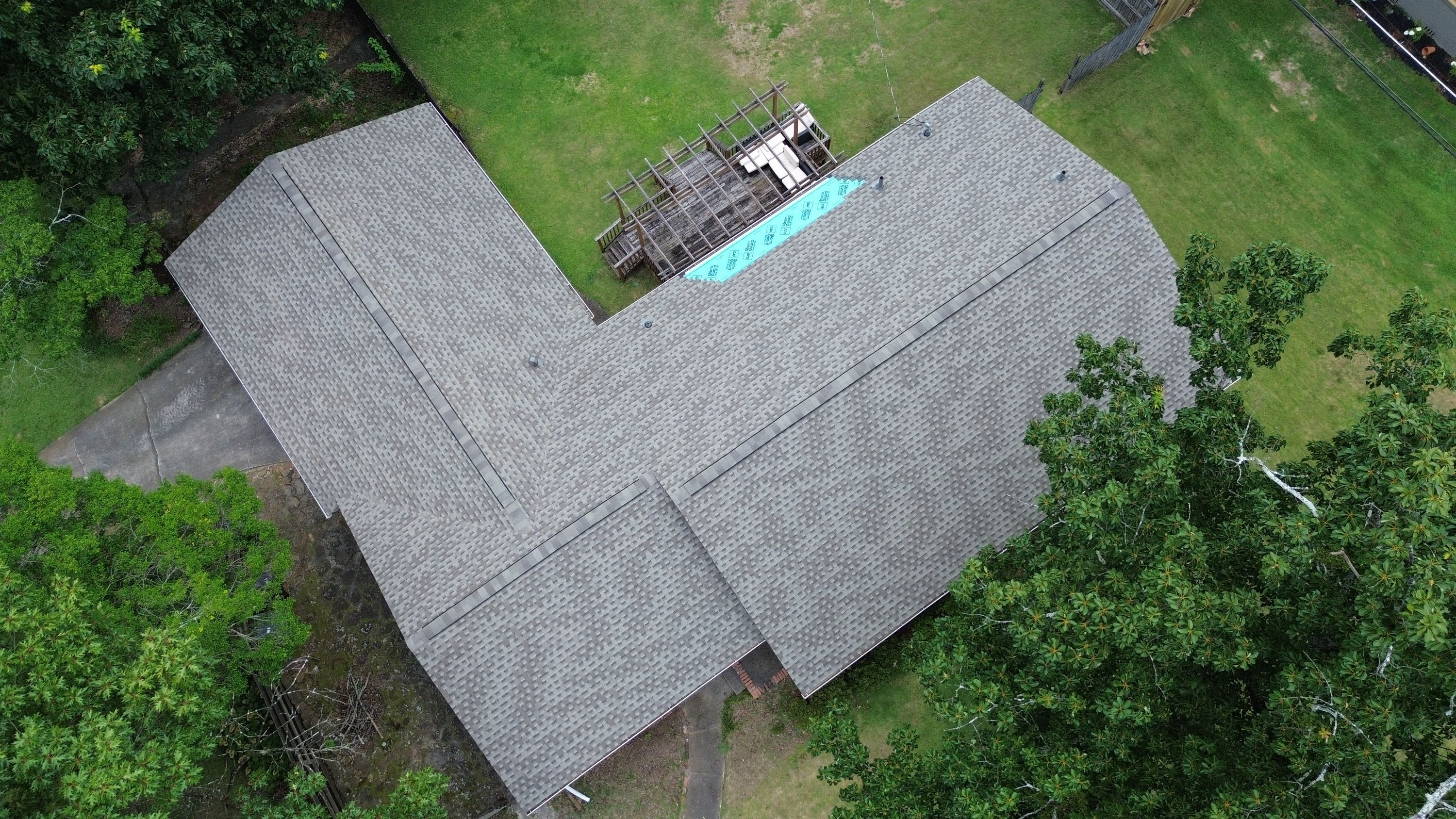 Drone photography shows grey shingles meeting a blue GAF leak barrier near a wooden deck on Columbiana Road.