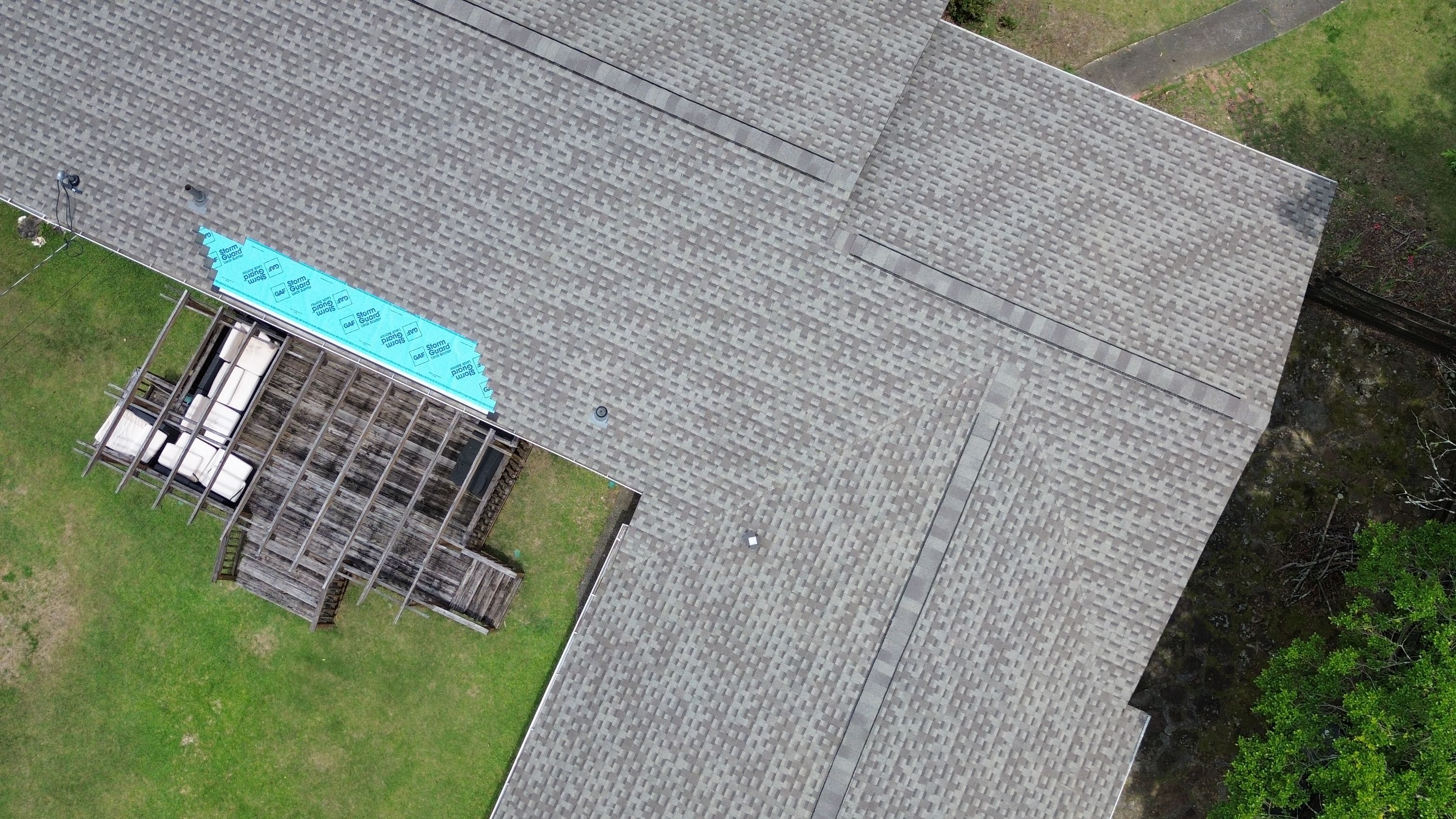 Clean, uniform rows of newly laid architectural grey shingles stretch across a wide residential roof plane.