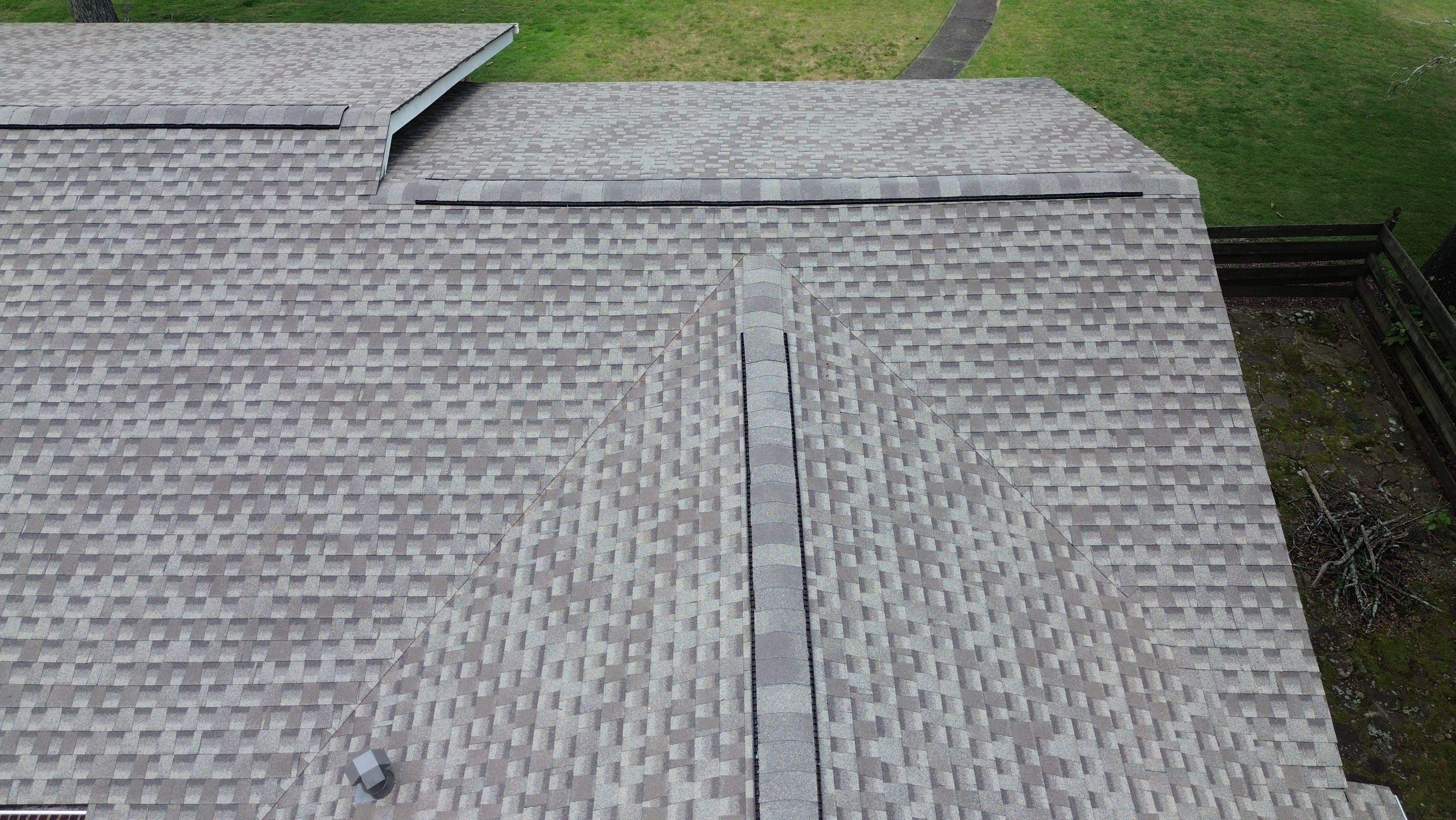 A clean ridge vent runs along the peak of the newly installed grey shingle residential roof.