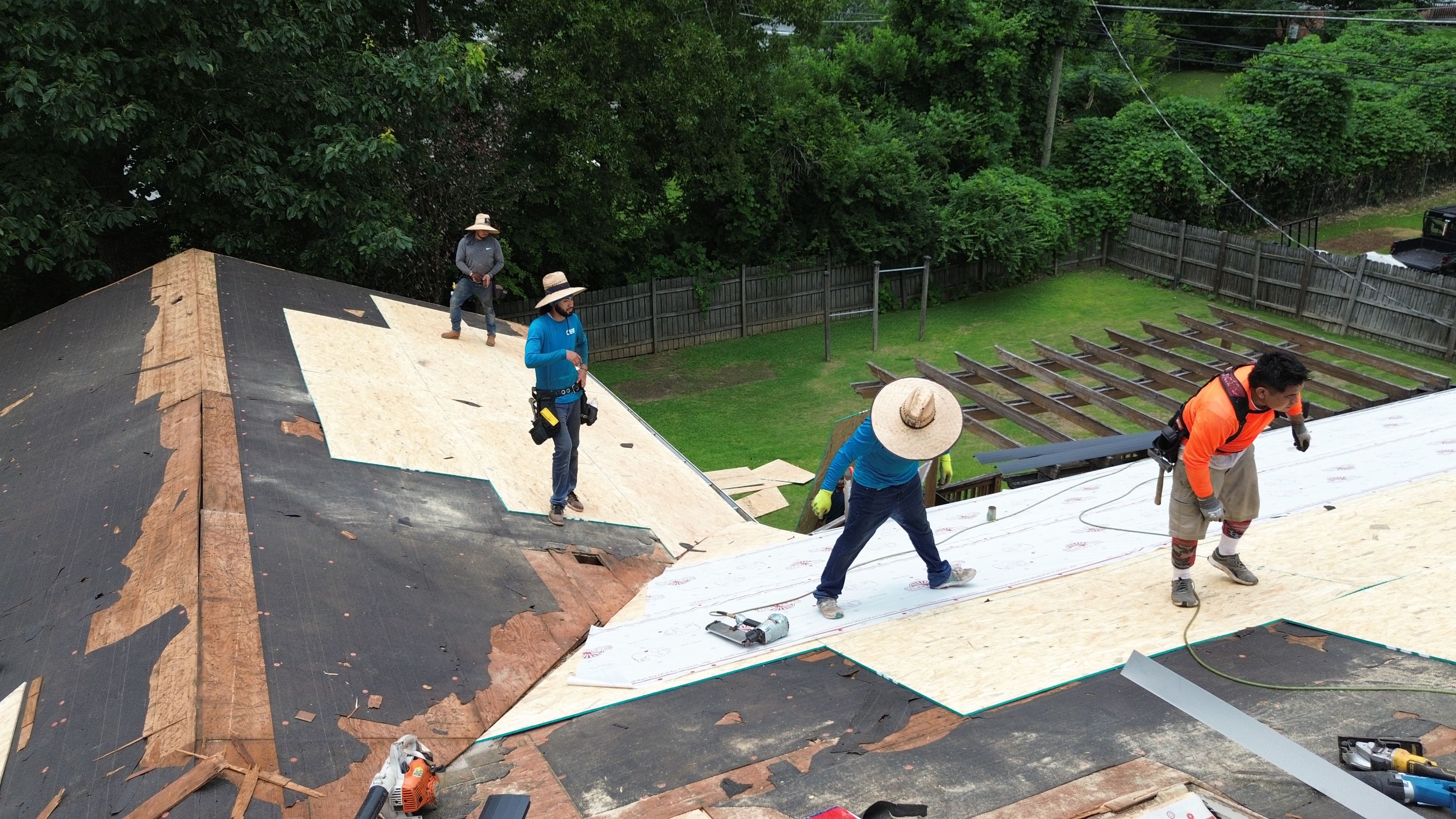 White underlayment goes down over fresh plywood decking during a roof replacement on Columbiana Road.