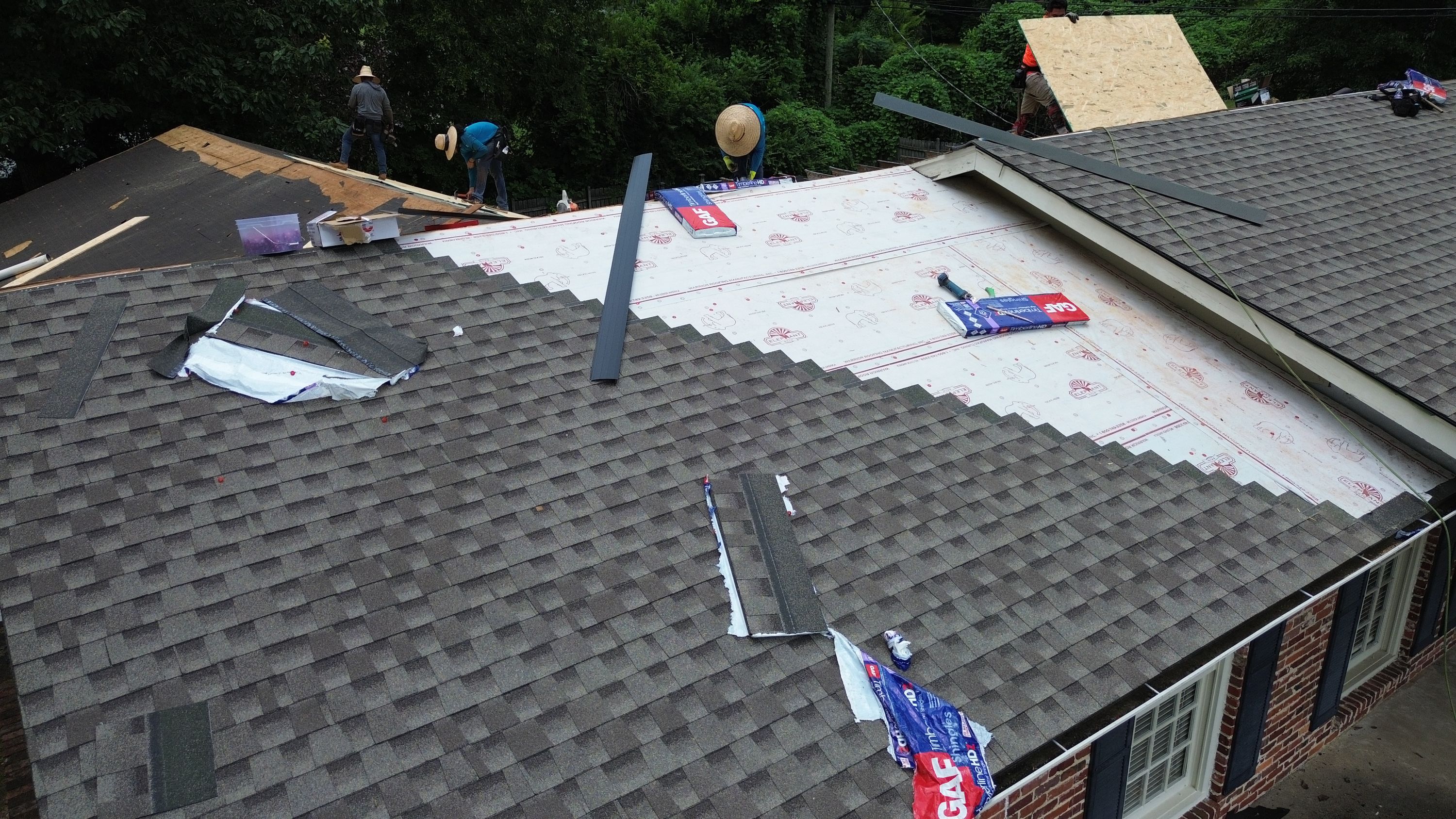 Fresh grey shingles meet white protective underlayment on an active roof replacement in Gentilly Forest.