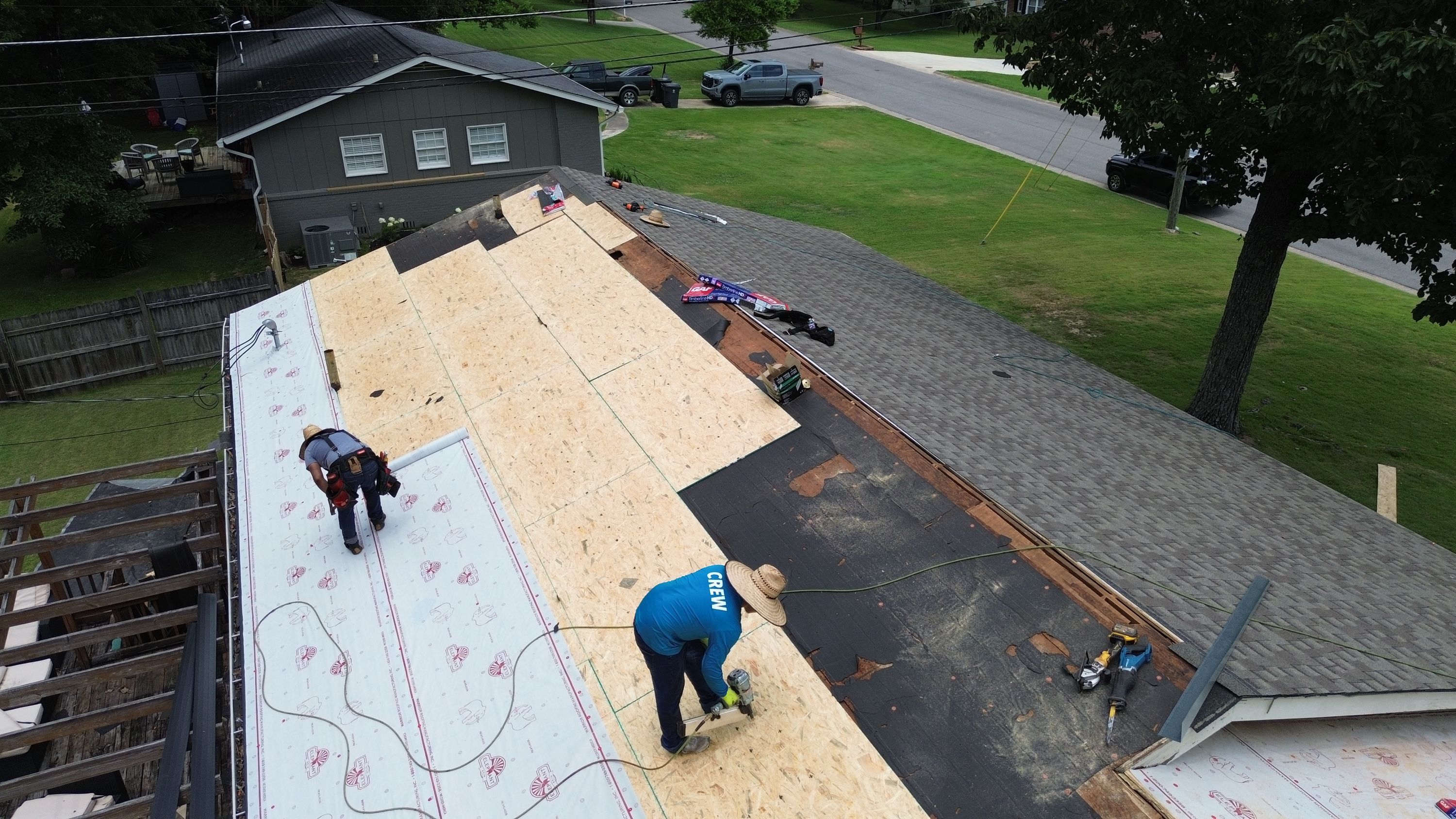 New OSB decking panels are nailed down beside old black underlayment during this residential roof replacement.