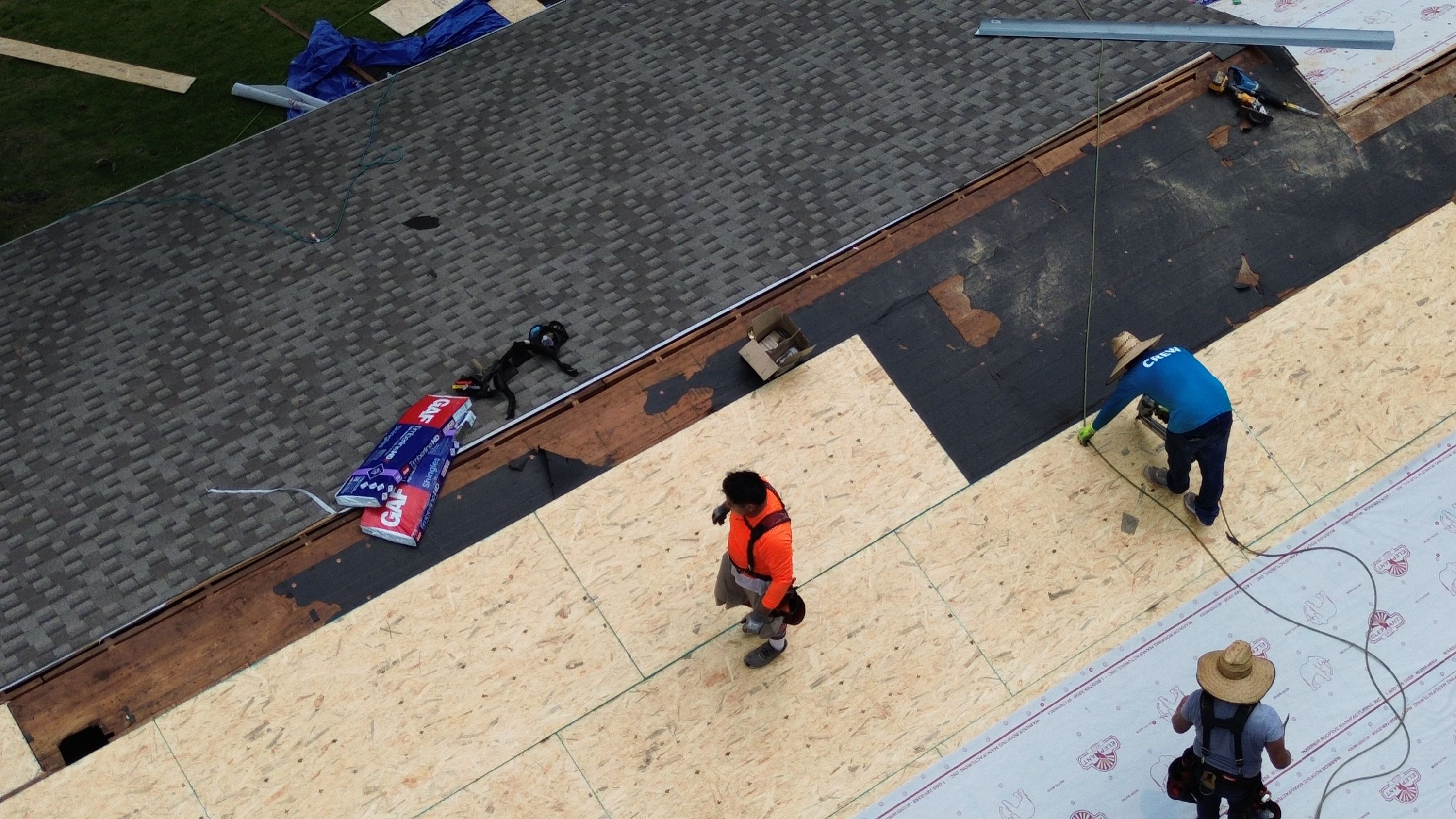 Plywood roof decking sits next to completed architectural shingle courses on Columbiana Road.