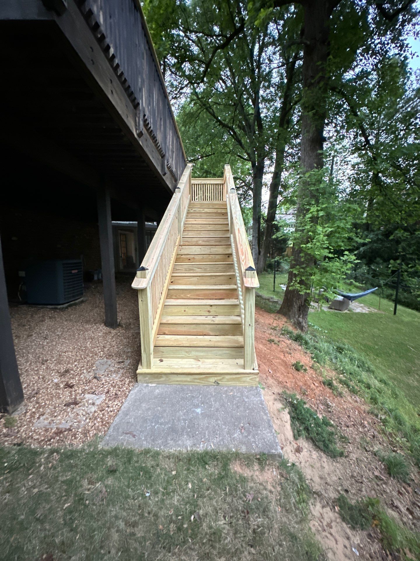 A newly constructed wooden deck staircase with railings leading to a backyard in Vestavia Hills.