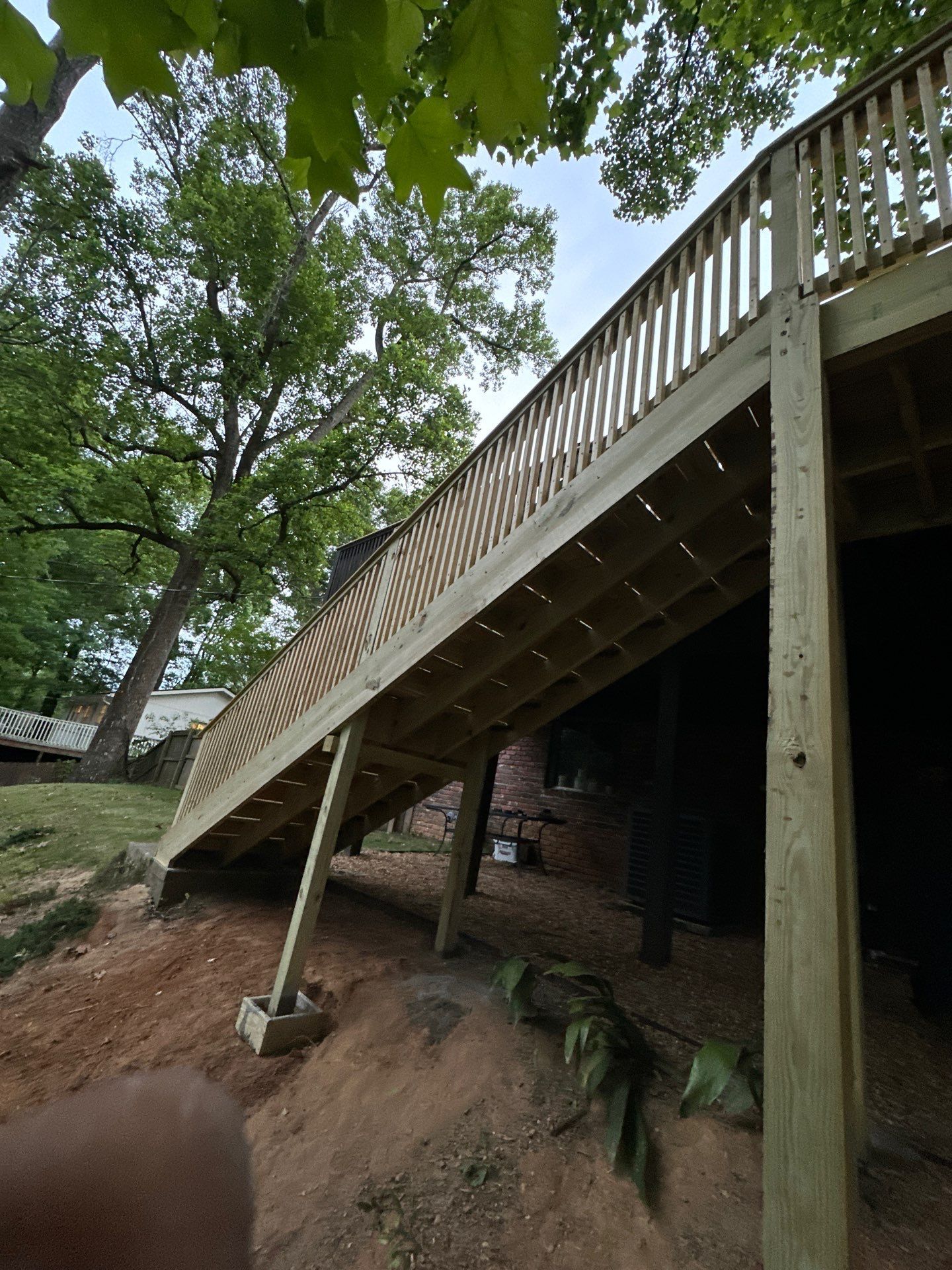 A newly constructed wooden deck with railings installed on a sloped yard in Vestavia Hills.