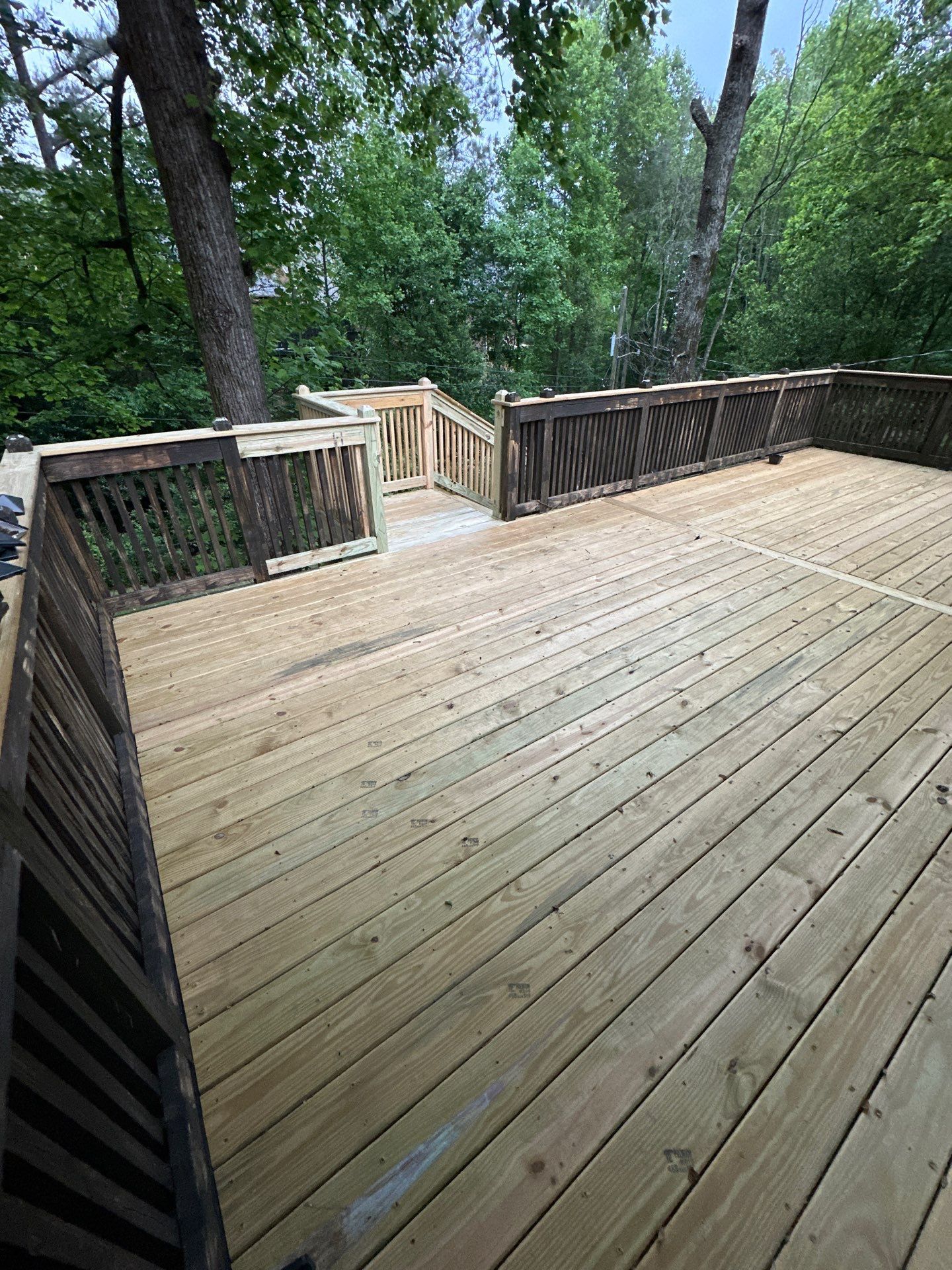 A newly constructed wooden deck featuring dark stained railings in a backyard in Vestavia Hills.