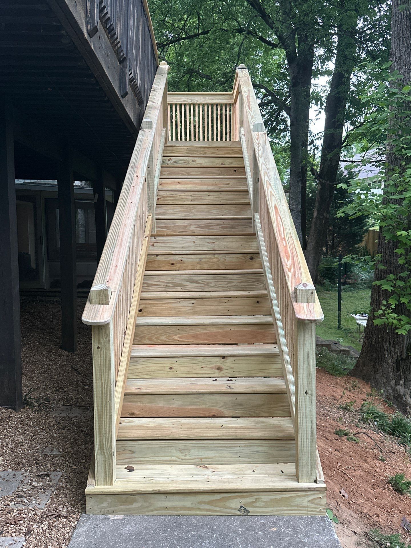 Newly constructed pressure-treated wood deck stairs leading to a backyard in Vestavia Hills.