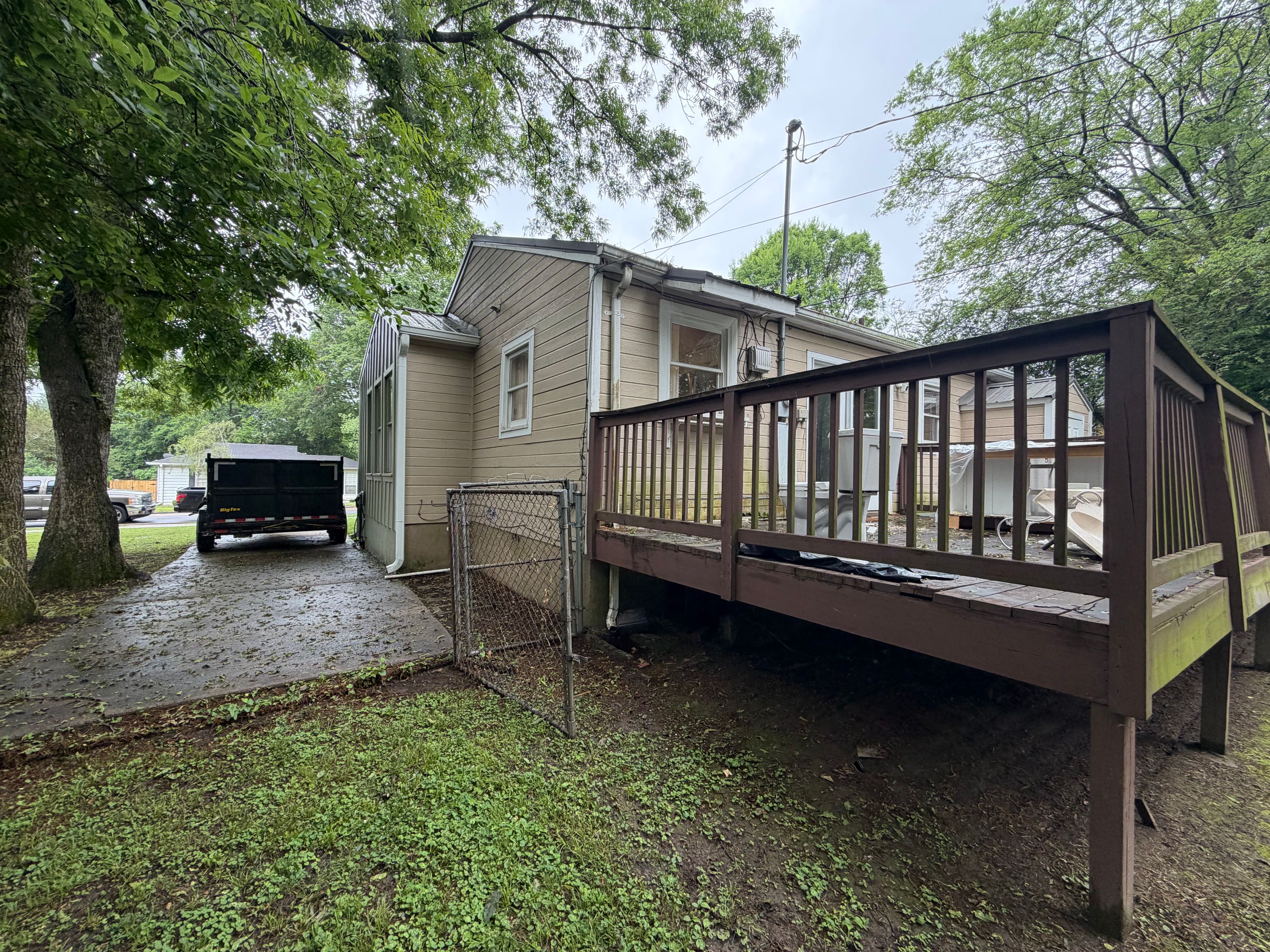A brown wood deck attached to a house in West Homewood with a trailer parked on the side driveway.