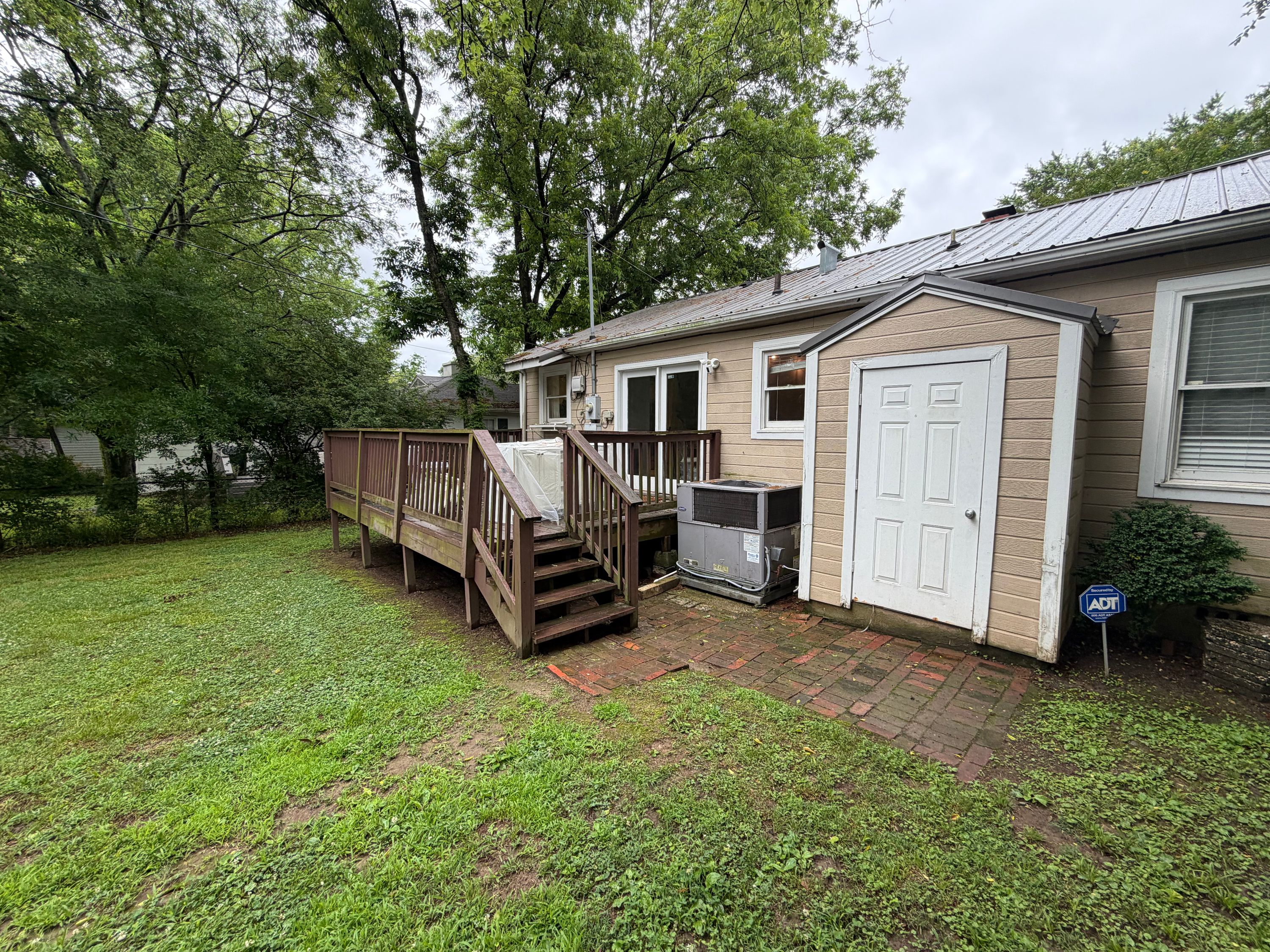 A wood deck with stairs attached to a West Homewood house featuring metal roofing and siding.