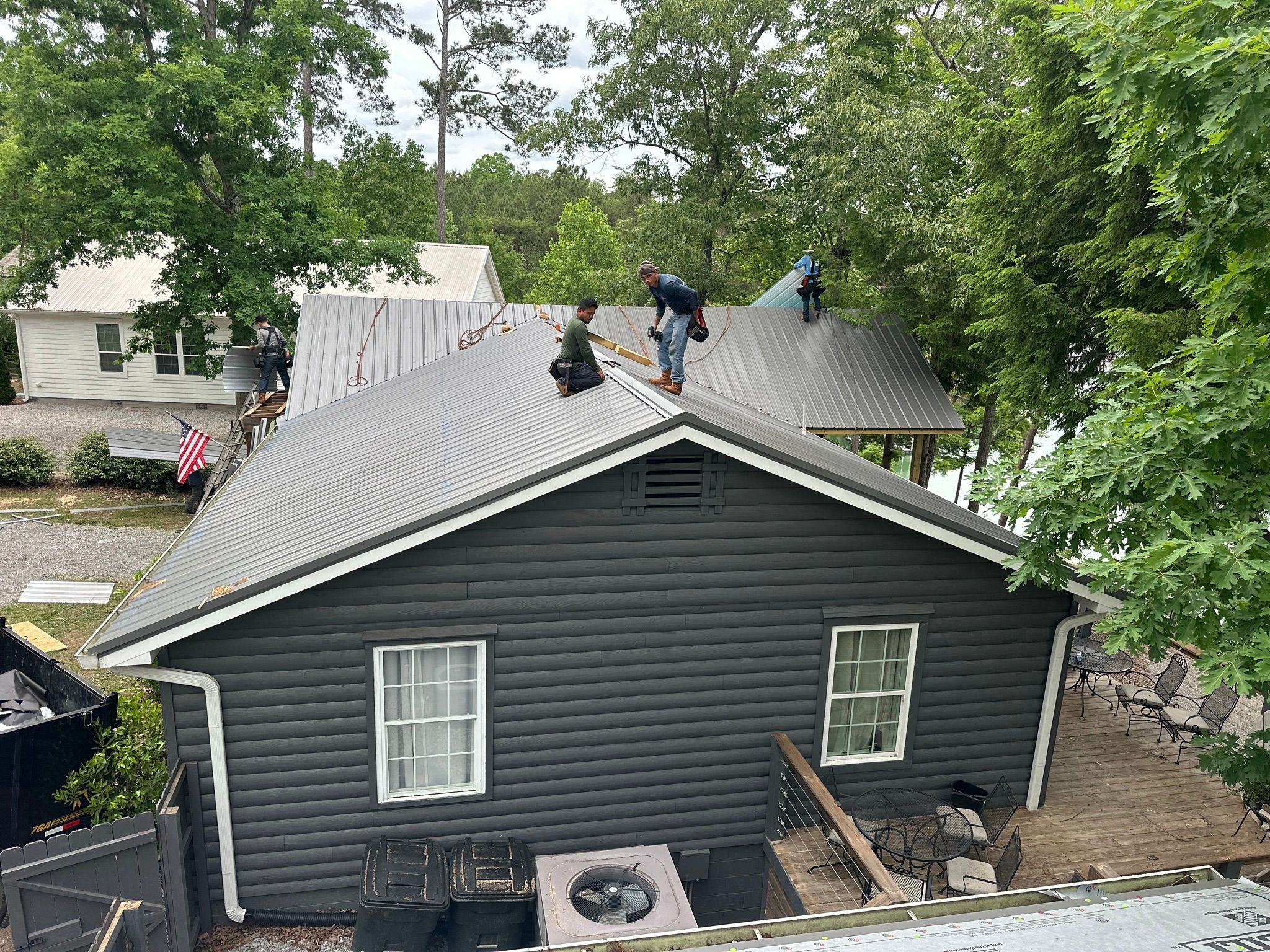 Workers installing a grey metal roof on a cabin home at Smith Lake in Jasper.