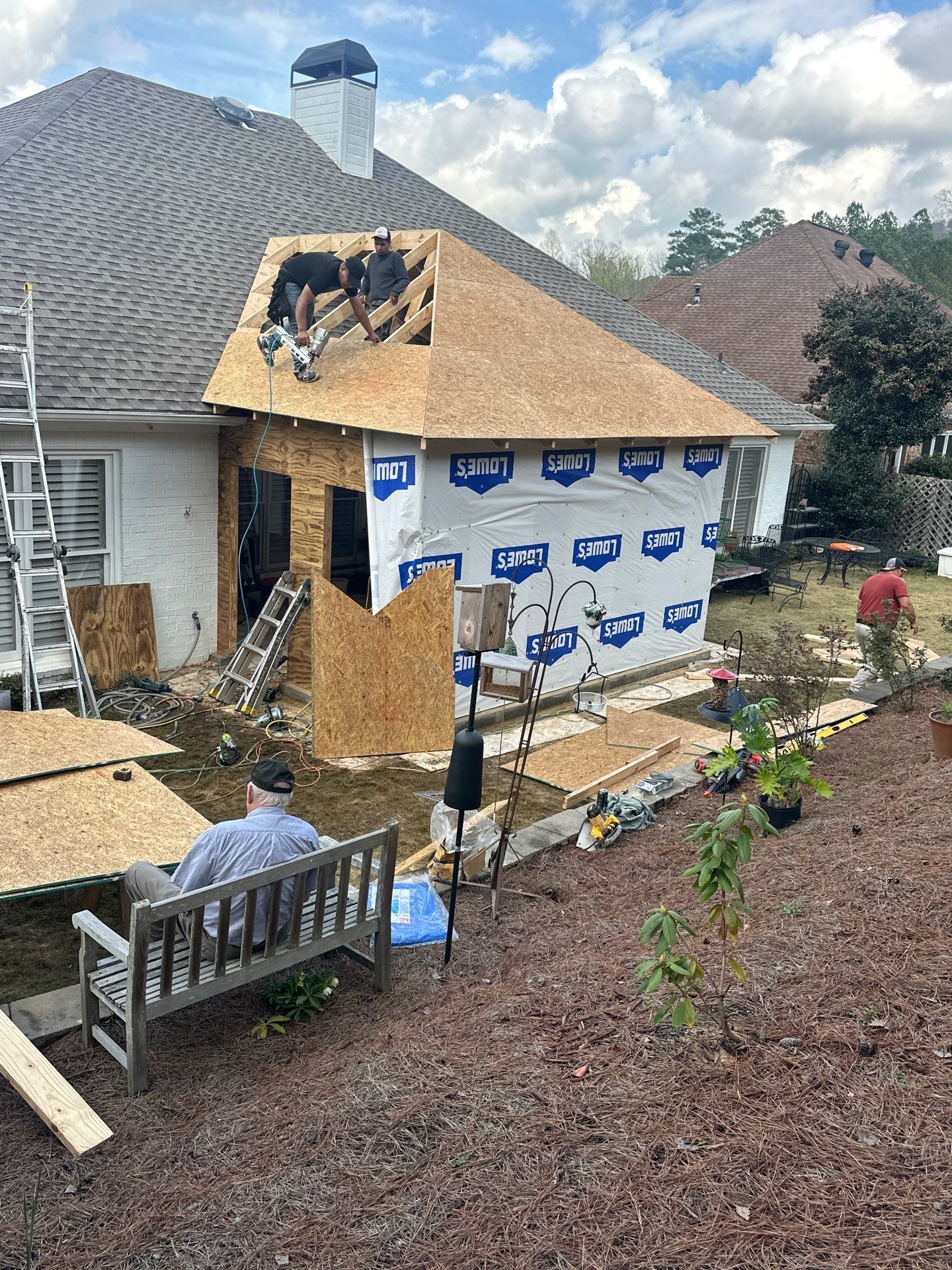 Roofers installing new plywood decking on a home addition during a roof replacement project in Hoover, Alabama.