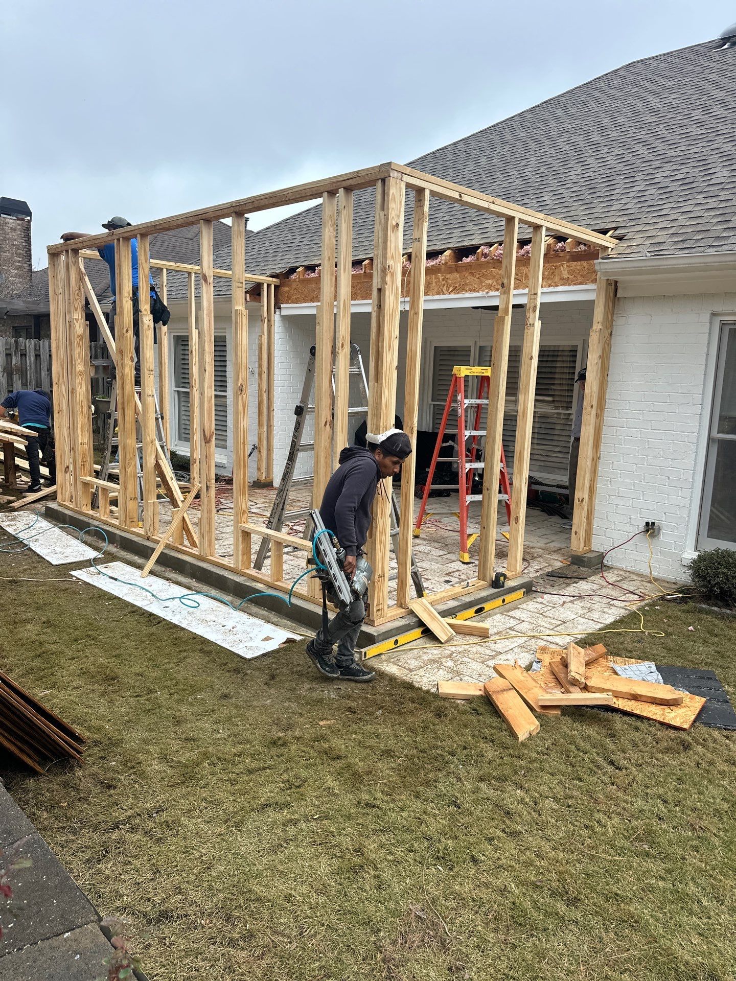 Contractors framing a home addition on a white brick residence in Greystone, Hoover, for a roof replacement project.