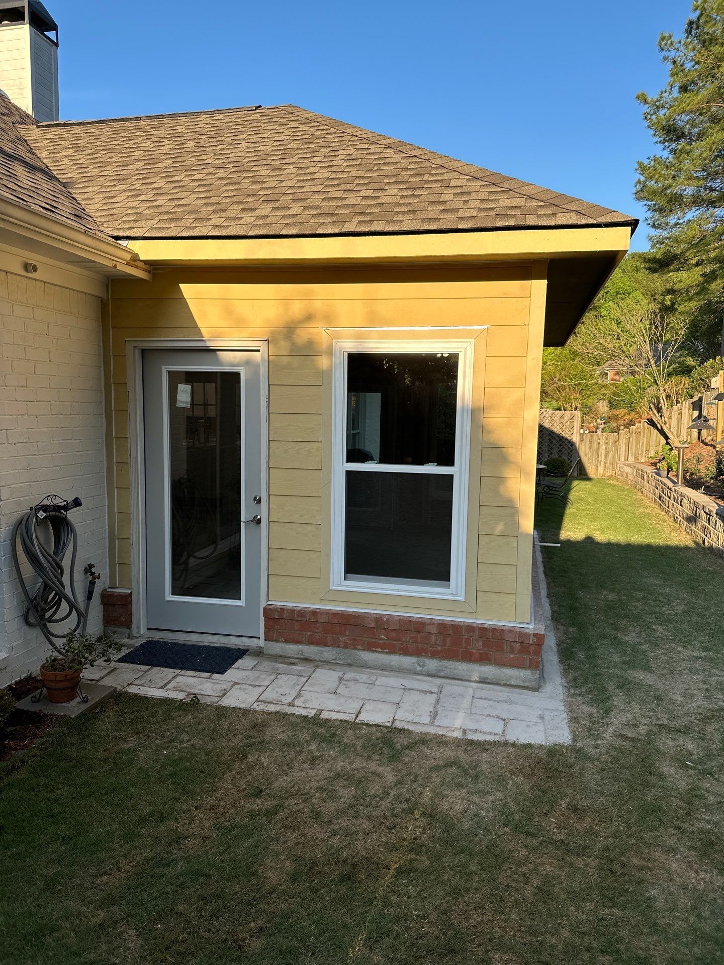 A yellow home addition with new siding, a door, and a window at a residence in the Greystone neighborhood of Hoover.